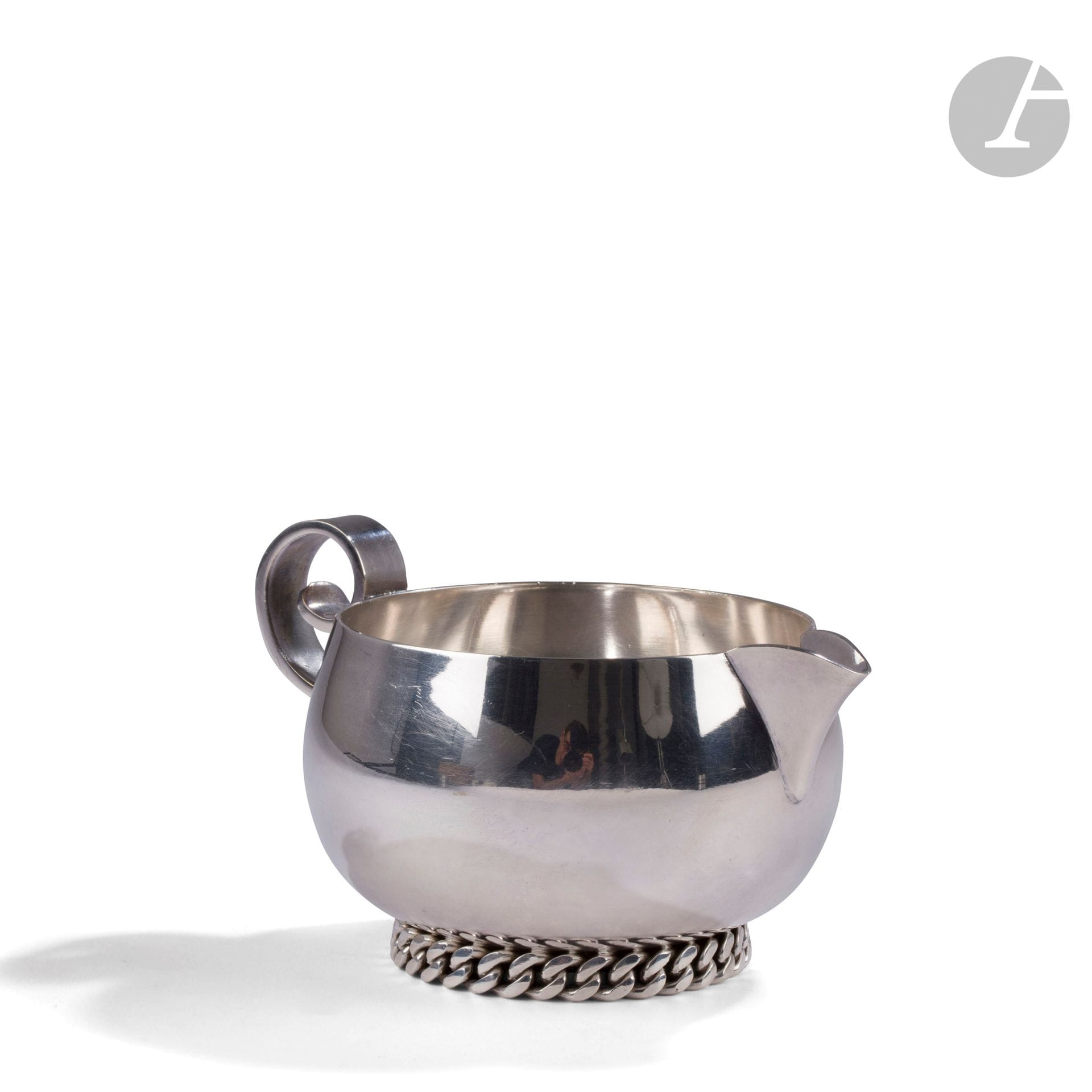 JEAN DESPRÉS (1889-1980) 
Verseuse à crème en métal argenté. Le corps renflé, l’anse en volute, le talon orné d’une gourmette à maillons plats en application. Signée J. DESPRÉS, à la pointe au revers. H. 8,5 cm – L. 15 cm