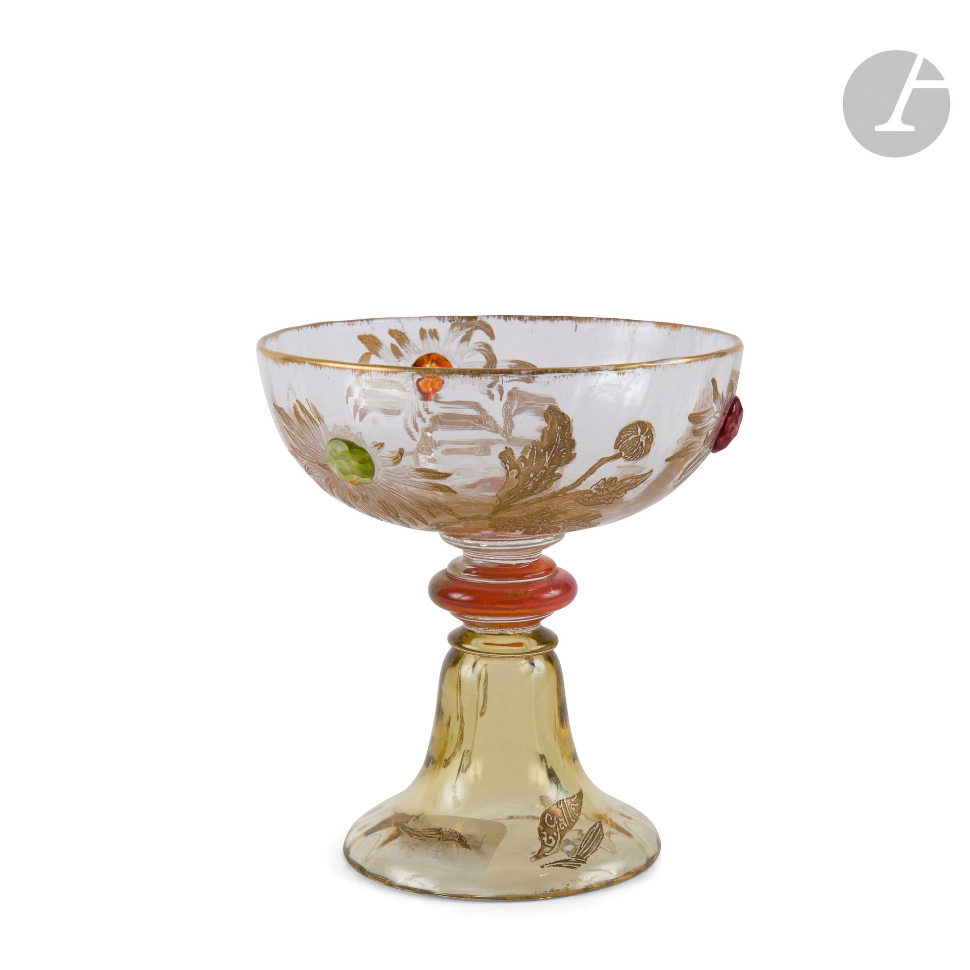 ÉMILE GALLÉ (1846-1904)
Chrysanthèmes du Japon
Rare verre à pied ; la base piriforme et la coupe réunies par une bague en verre teinté rose collée à chaud. Épreuve en verre légèrement teinté ; le décor titre gravé et rehaussé à l’or, les cœurs de fleurs figurés par des cabochons collés à chaud sur des fond colorés (deux rouges, un vert) et entièrement repris en gravure à froid à la façon d’un martelage. Vers 1902. Signé E. GALLÉ dans un cartouche en forme de feuille et gravé et rehaussé à l’or. H. 11 cm – D. 10 cm

Collections publiques :
- Musée de l’École de Nancy, Nancy – Une légère variante conservée dans les collections de cette institution sous le numéro d’inventaire TT.83.34.
- Musée des Arts Décoratifs, Paris - Une légère variante conservée dans les collections de cette institution sous le numéro d’inventaire 41932.

Bibliographie :
Collectif – Émile Gallé et le verre – La collection du musée de l’École de Nancy – Somogy éditions d’art, Paris, 2004-2014, Éditions du musée de l’École de Nancy, 2004-2014. Une légère variante reproduite page 86 sous la référence 93.