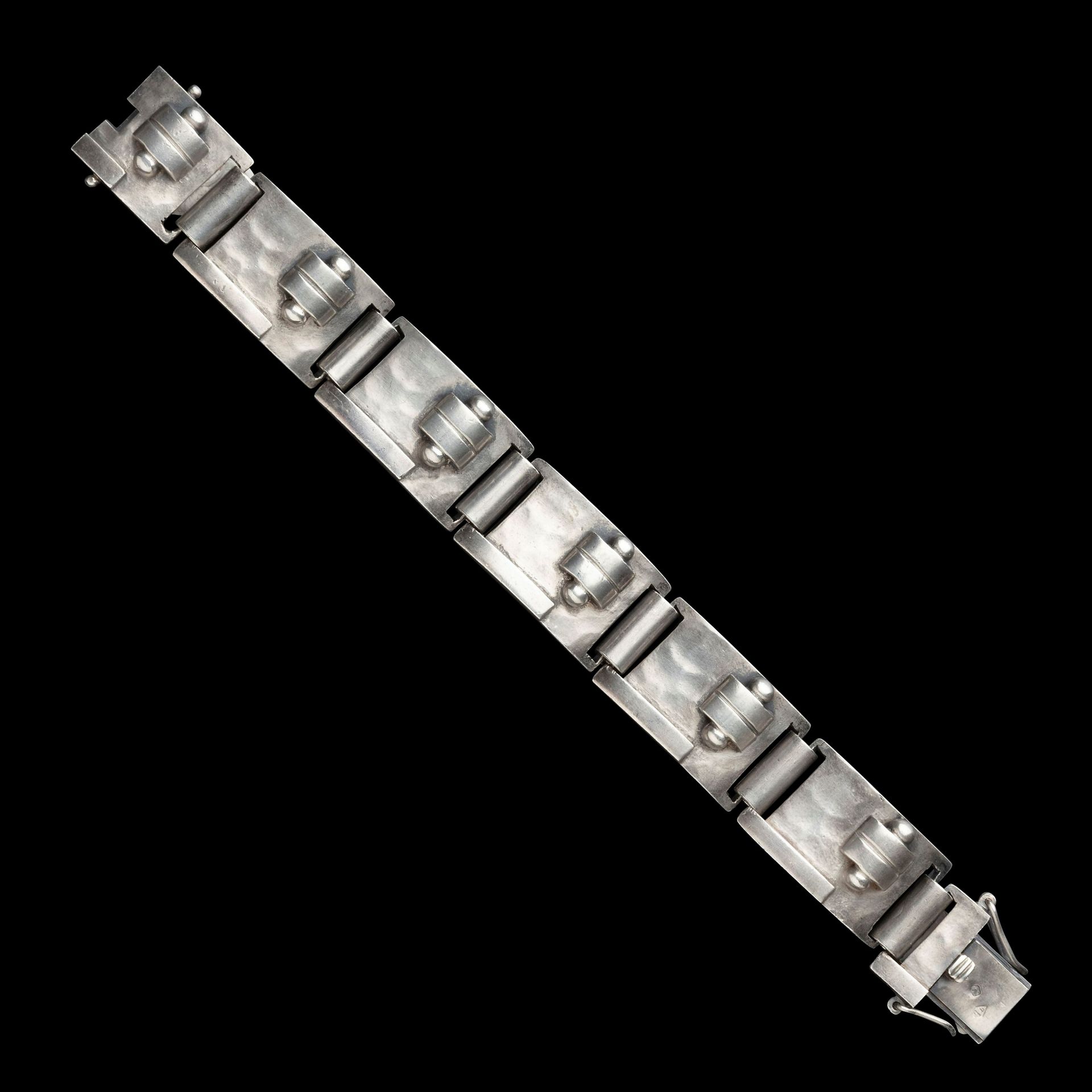 JEAN DESPRÉS (1889-1980)
Rare bracelet moderniste articulé en argent. Les six plaques concaves reçoivent des décors, en applications, de motifs géométriques (barrettes, languettes et sphères) sur fond martelé. Signé J. DESPRÉS à la pointe au revers de l’une des plaques et porte les poinçons de Maître Orfèvre et de garantie sur le fermoir. Poids : 70,32 g

Provenance :
- Ancienne Collection M. & Mme C. (Magny près d’Avallon – France), œuvre acquise par ces derniers directement auprès de l’artiste.
- Arts décoratifs et sculptures du XXe siècle – Vente Ader-Nordmann-Dominique, Hôtel Drouot, le 2 juin 2017. Œuvre présentée sous le numéro 96 du catalogue.
- Collection particulière européenne.