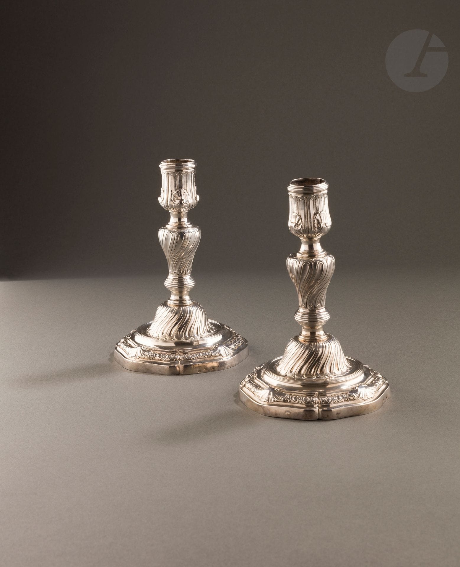 PARIS 1761 - 1762
Pair of silver toilet torches with unscrewable shafts, the base with four contours prolonged with oves, interlacing and shells. The umbilicus with twisted channels on an amatized background in recall on the shaft in reverse movement. The tap is enhanced with double shells and straight channels. 
Master goldsmith : Pierre-Louis REGNARD, received in 1759
Weight : 716 g - height : 15,8 cm
Marks : in the binnacle and on the reverse, punched with a crab on the edge