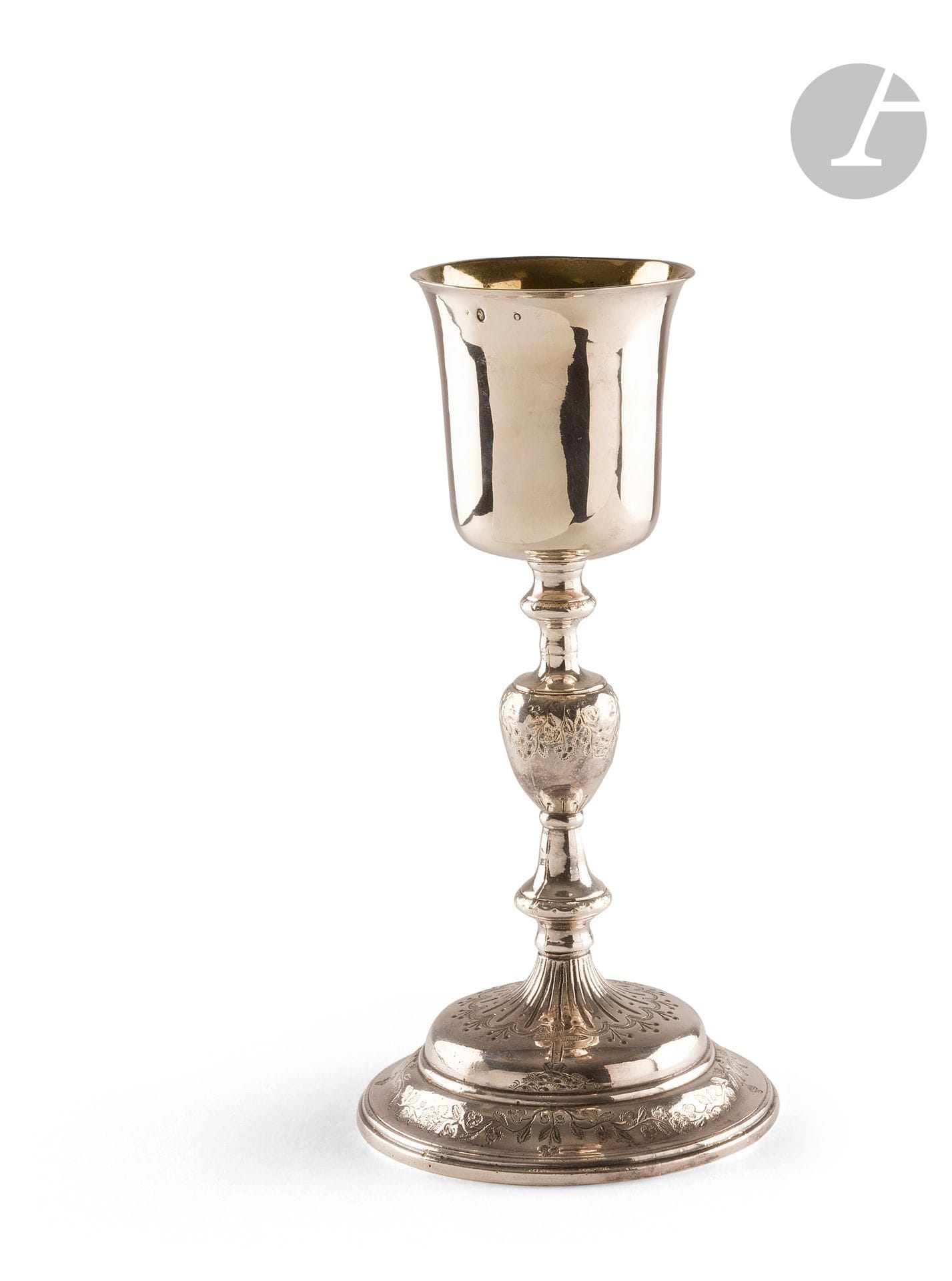 PARIS OR PROVINCE 1819 - 1838
Chalice in silver plated metal, the cup in silver, the foot in metal. It rests on a circular base engraved with a trellis prolonged on the collar of a decoration alternating points, gadroons of alternate sizes in pearled and amatized poly-lobed frames framing a cross. The knot is engraved with flowers and foliage and the cup is plain.
Weight : 539 g - height : 26,6 cm - diameter of the foot : 13,1 cm
Marks : old man and guarantee on the cup (first figure illegible), repointed with a crab
Condition : old repairs on the foot, wear on the knot of the stem