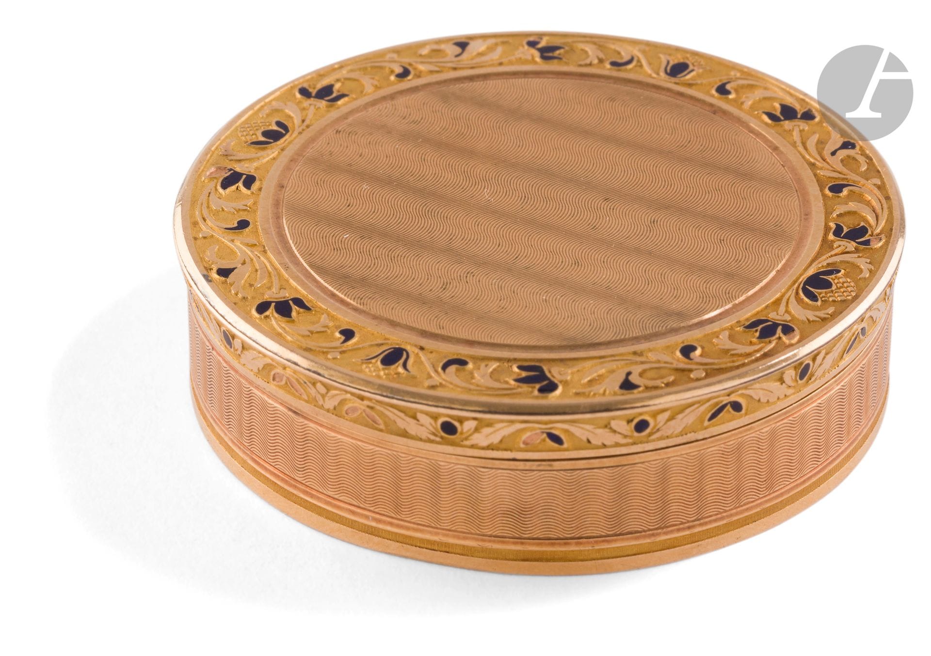 PROVINCE 1798 - 1809
Box or candy box in gold (750 / °°°) enamelled for part blue. The lid and the reverse side are chiseled with the same guilloche pattern of waves bordered by a blue enamelled floral border. Engraved on the rim CATHERINE MEHU FEMME BAYARD. 
Gross weight: 47 g - diameter: 5.5 cm - height: 1.5 cm
Condition: some enamel missing

