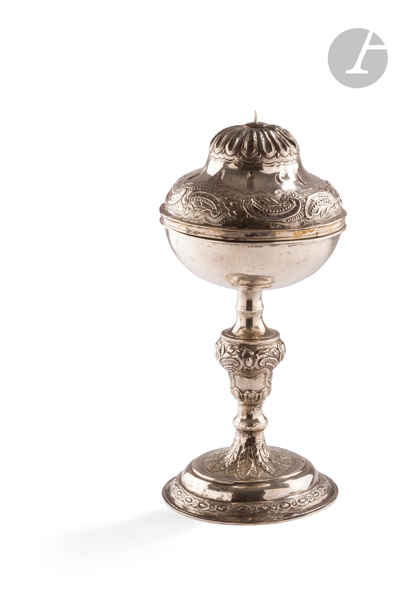 FRANCE XVIIIe SIÈCLE
Ciboire en argent, l’intérieur de la coupe en argent doré. Le pied circulaire est repoussé d’oves de tailles alternées sur fond amati, le départ du fût de larges feuilles lancéolées et le noeud d’enroulements feuillagés en rappel sur le couvercle. La coupe est en argent uni. Le couvercle est sommé d’un rang de larges oves et de dards encadrés d’amatis. 
Poinçonné en maître abonné DG une étoile non identifié
Poids : 391 g - hauteur : 26,5 cm
État : déchirure à l’intérieur de la coupe, croix manquante