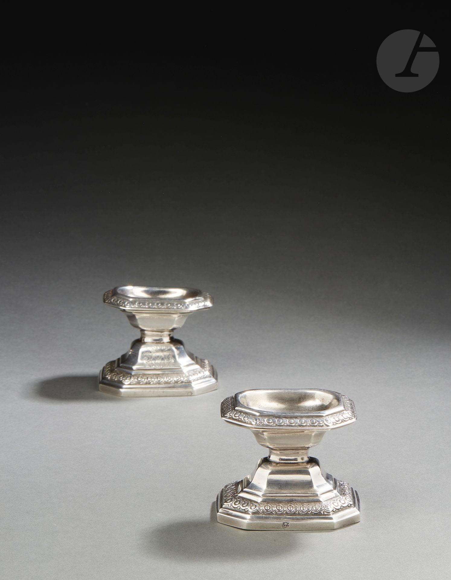 RENNES 1725 - 1726
Paire de salières en argent. Rare modèle français rappelant celui des salières de Liège dites « diabolo ». Elles reposent sur une base hexagonale à pans coupés en rappel sur la bordure supérieure, repoussée d’oves et d’entrelacs sur un fond amati. La partie inférieure sur les doucines est gravée des armoiries de jeune fille de René-Caroline-Victoire de Froulay (1714 - 1803), mariée en 1737 au marquis de Créquy (1686 - 1741). Elle tint salon à Paris durant tout le XVIIIe siècle.
Maître orfèvre : Jacques-Eloy PIGEON, reçu en 1725
Poinçons : poinçonnée deux fois du maître orfèvre dans le fond et la base, décharge entre 1722 et 1726.
État : deux petits trous aux deux angles supérieurs d’une salière
Poids : 219 g - hauteur : 6,5 cm - longueur : 8 cm - largeur : 6,5 cm
