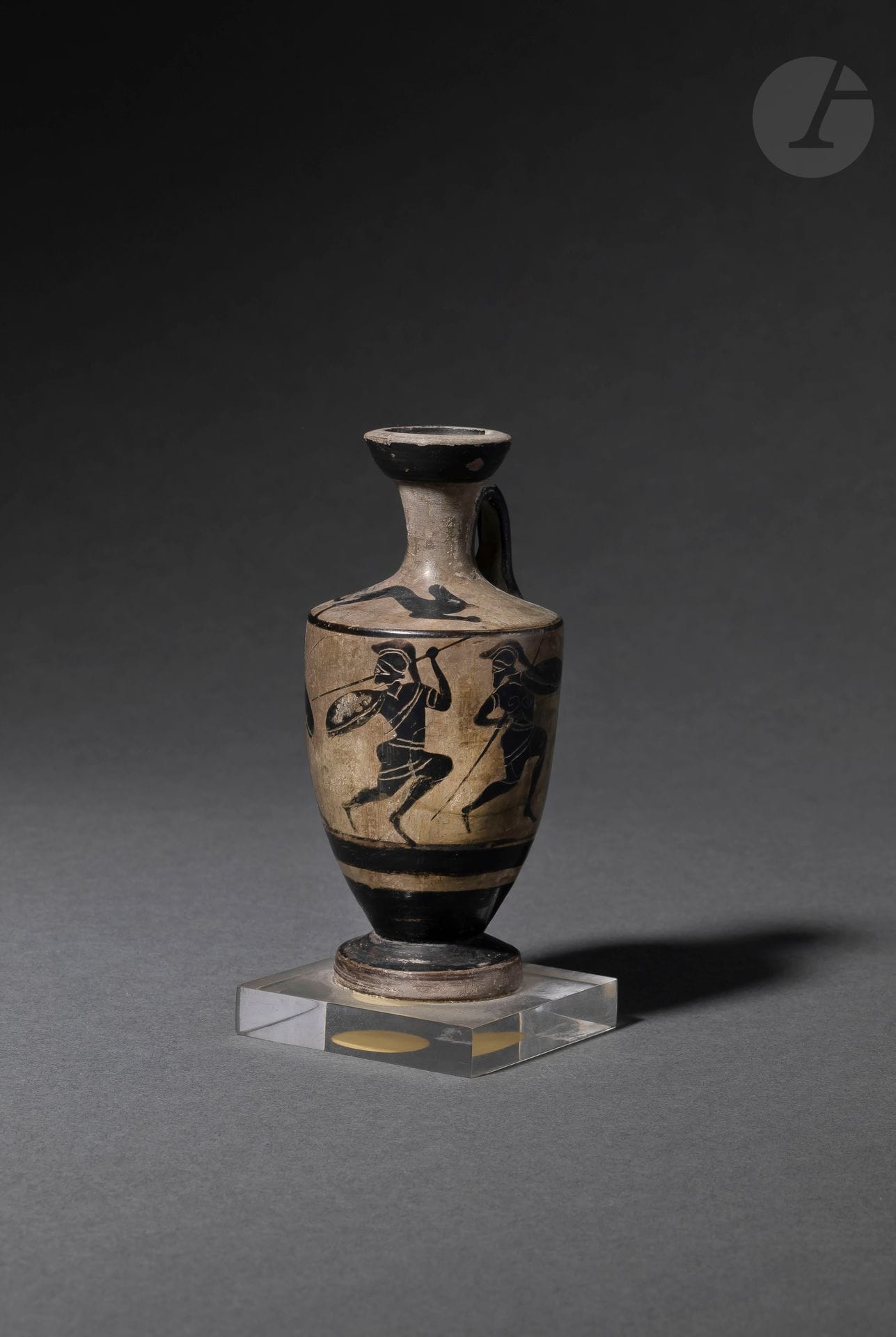 Lécythe à décors d’hoplites sur la panse et d’animaux courant sur le col 
Céramique à figures noires. Restaurations. 
Grèce, c. Ve siècle avant J.- C. 
Hauteur : 11,5 cm 
 
Provenance : 
Étiquette de la collection Claude de Muzac sous la base du socle.

A Greek Black-Figure Lekythos, c. 5th century BC