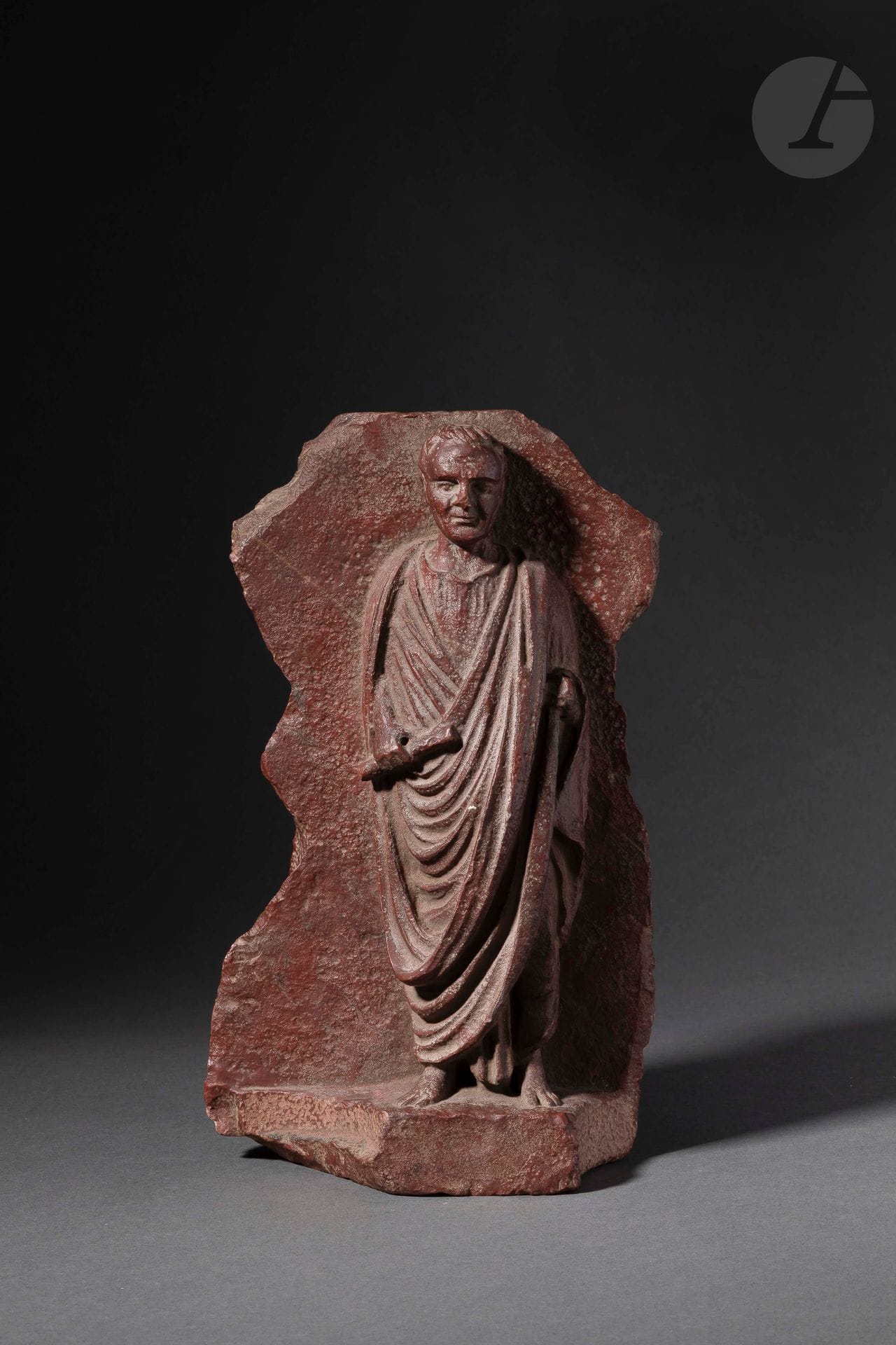Stèle sculptée en haut-relief d’un togatus 
Porphyre. 
Dans le style romain 
Hauteur : 30 cm ; largeur : 17 cm

Provenance :
Collection Poindessault constituée au début des années 1970.

A Roman Style Porphyry Stele Carved in Relief with a Togatus