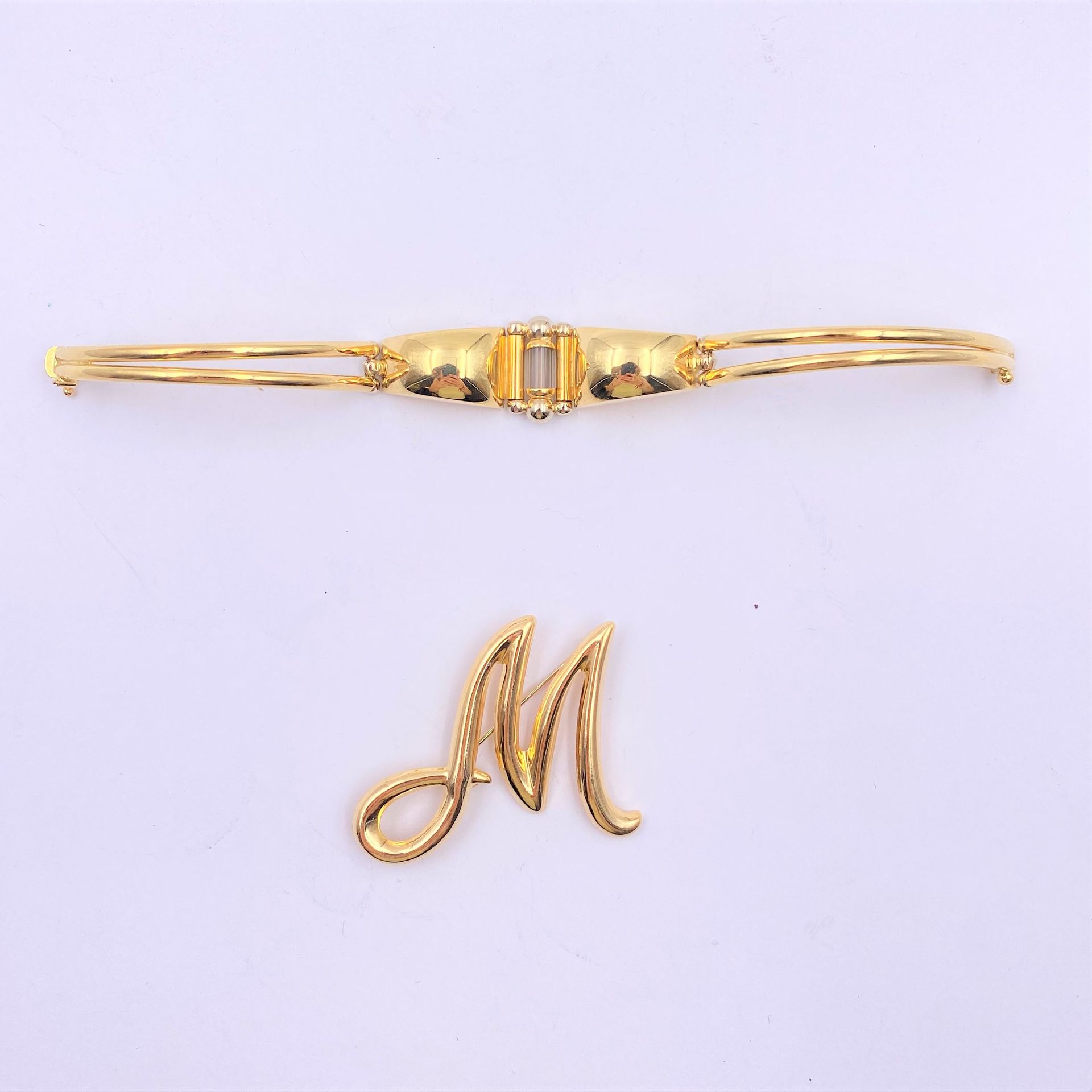 Lot de deux bijoux en or (18K). Poids brut: 20,2 g

- un bracelet articulé en or (18K) 

- une broche "M"

Frais acheteur pièces et lots en or : 9,6% TTC -  8% HT 