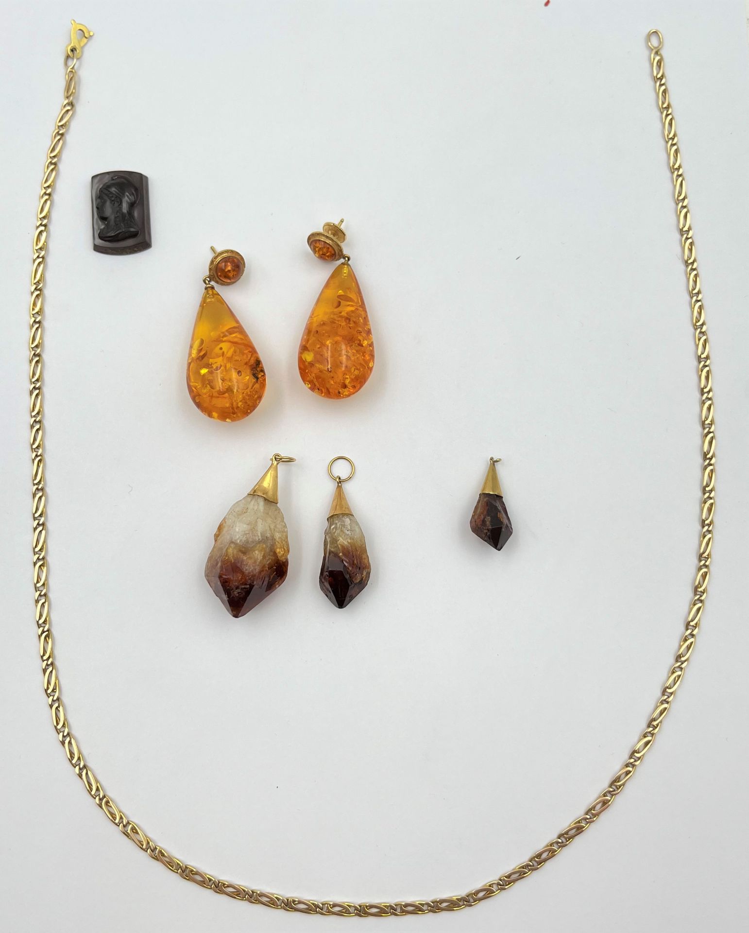 Lot de bijoux en or (14K et 9 K). Poids brut: 51,7 g

- une chaine (56 cm) en or (9K). Poids: 17 g

- 3 pendentifs cristaux montés en or (14K). Poids brut: 18,7 g

- une paire de Boucle d'oreilles (ambre?) avec attache en or (18K). Poids brut: 15 g

Frais acheteur pièces et lots en or : 9,6% TTC -  8% HT 