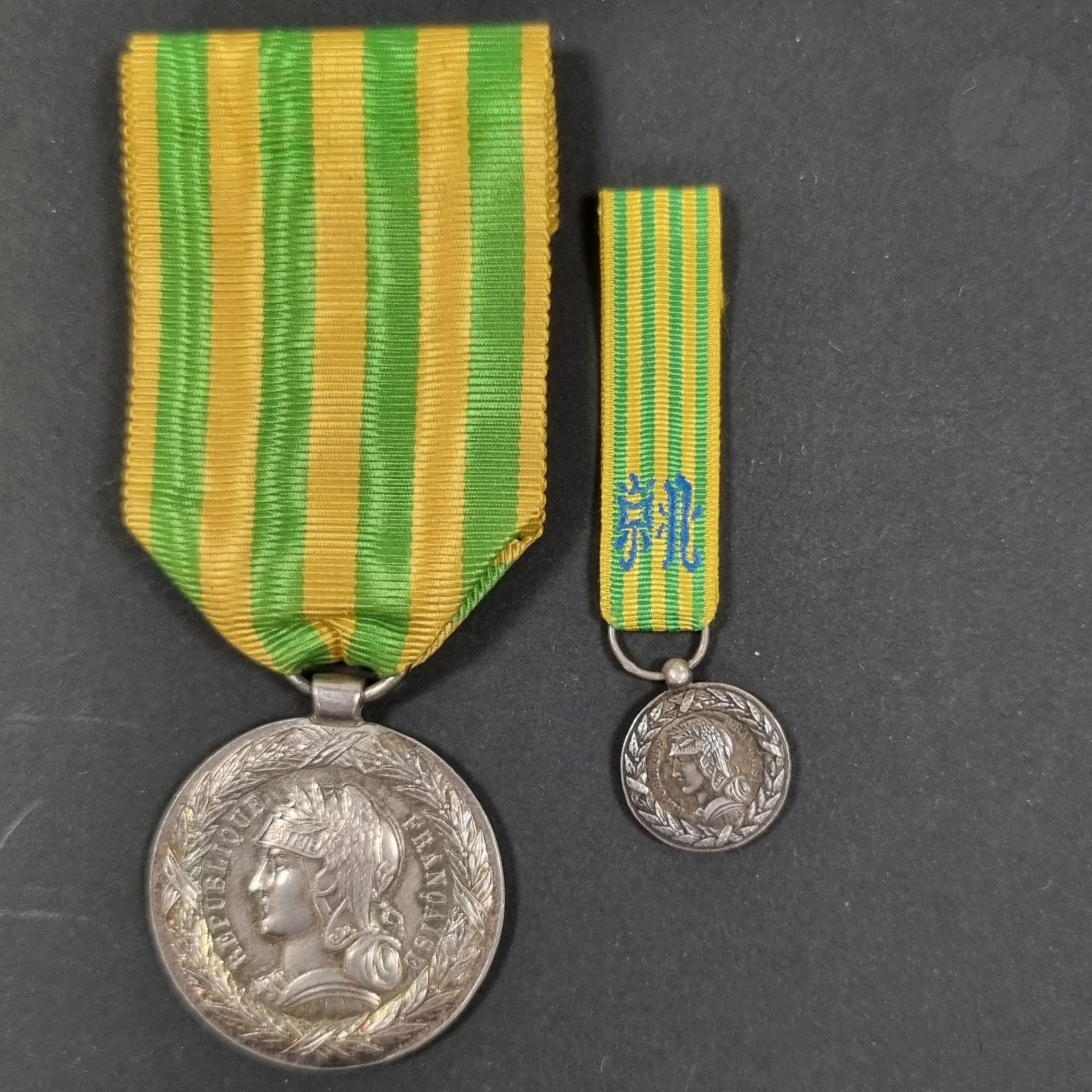 FRANCE 
MÉDAILLE DU TONKIN (1885)
Médaille en argent, modèle de l’armée de terre. Bélière tube. Ruban. 
29 mm - Poids brut :15 g
Avec une demi-taille (14 mm) de ce modèle en argent. Poinçon tête de sanglier, bélière boule. Ruban d’essai. Poids net : 2,5 g 
T.T.B.