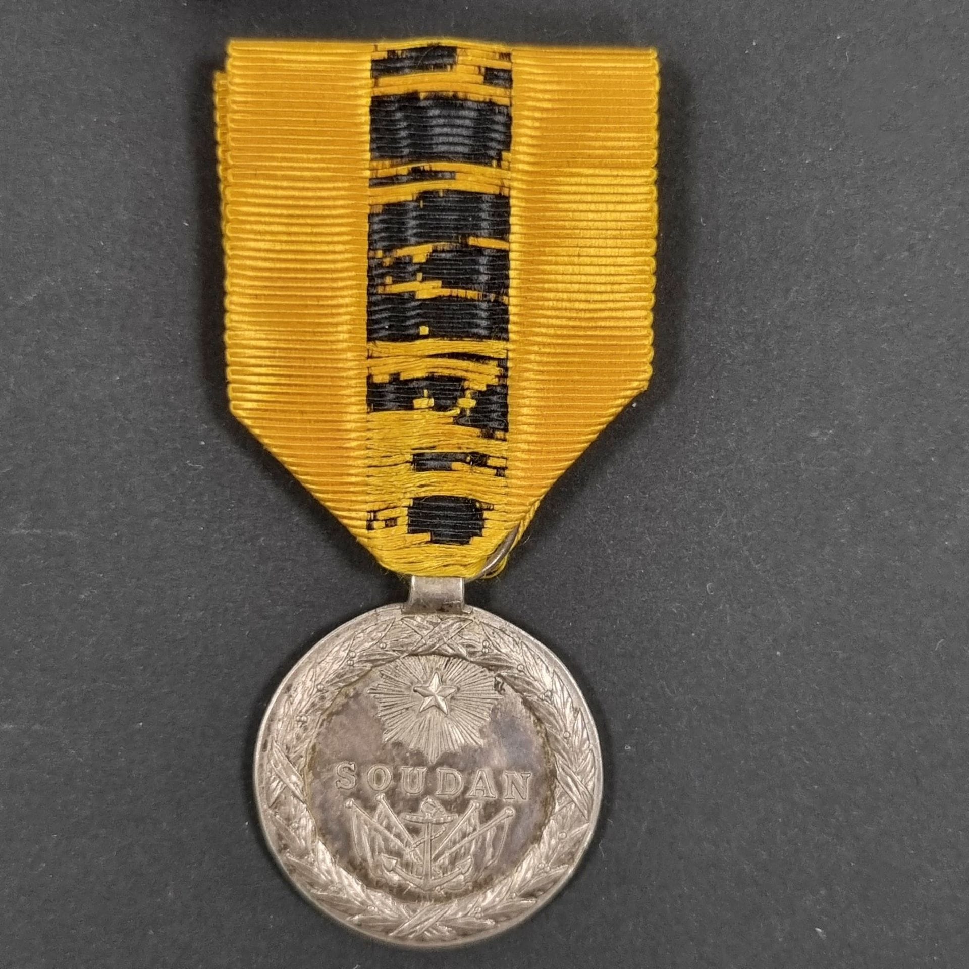 FRANCE 
MÉDAILLE DE L’EXPEDITION DU SOUDAN (1890-1892) 
En argent, à bélière tube. 
Ruban ancien (usé). Poinçon au cygne. 
30 mm - Poids net : 12,3 g 
T.B. à T.T.B. (usures sur la tranche).