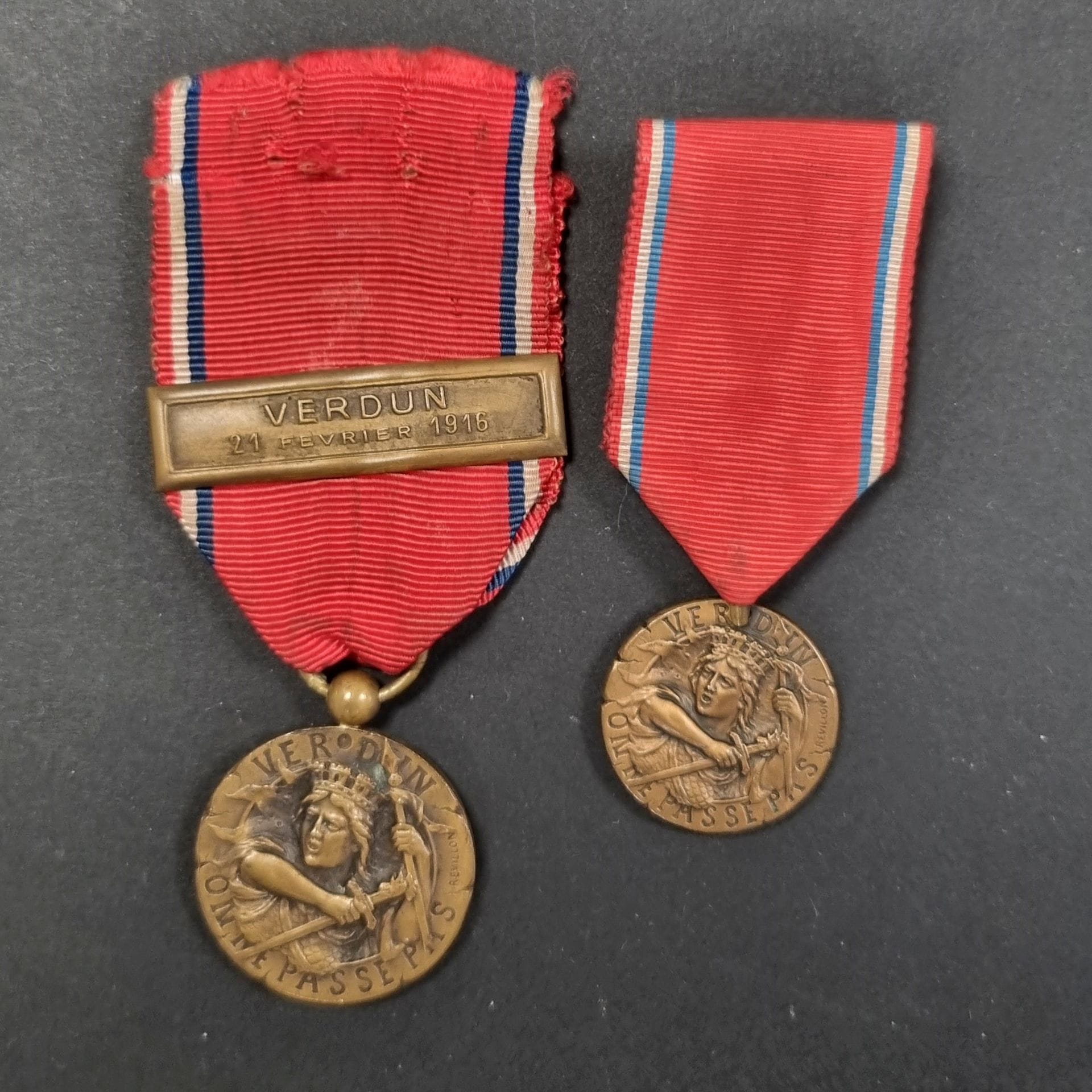 FRANCE 
Médaille de Verdun. 
Deux modèles de Rébillon, en bronze. 
Une ordonnance à bélière boule et agrafe « VERDUN 21 février 1916 » et une réduction à bélière « pince » et ruban plié. 
25 et 20 mm 
T.T.B. à SUP.