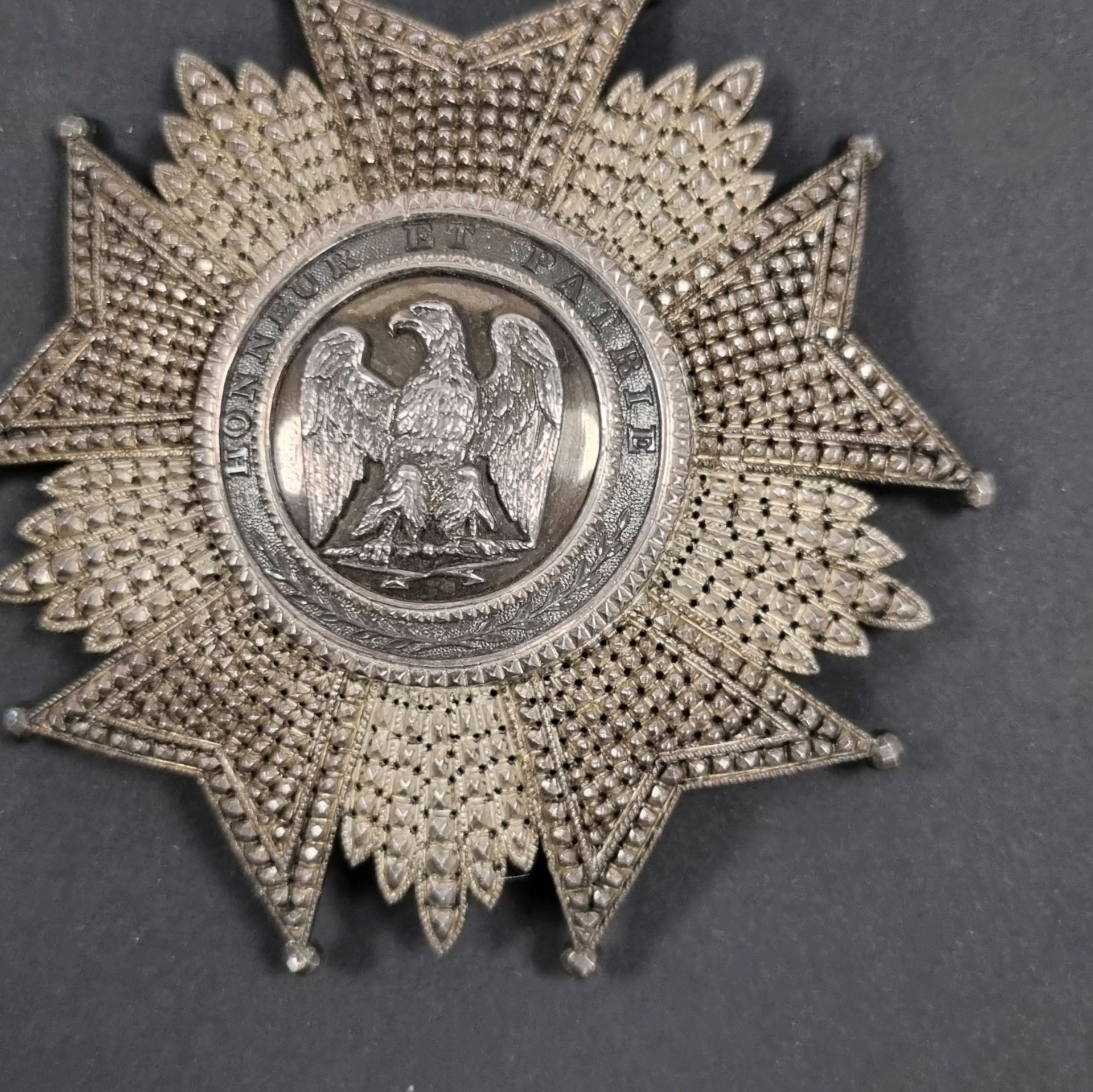 FRANCE 
ORDRE DE LA LÉGION D’HONNEUR (1802) 
Plaque de grand officier ou de grand-croix modèle du Second Empire. 
En argent entièrement travaillé à pointes de diamant, repercé. 
Le centre en plusieurs parties, à motif à l’aigle tête à gauche sur foudre, tête à gauche. Légende « HONNEUR ET PATRIE » sur fond grenu, à bordures dentelées. 
Revers à deux crochets et épingle basculante avec pastille du fabricant « N°46 KRETLY PALAIS ROYAL PARIS ». Crochet poinçonné à la tête de sanglier 
81 mm - Poids brut : 53 g 
T.T.B. à SUP. 

Il s’agit d’une plaque de fabrication privée, vendue par Kretly.