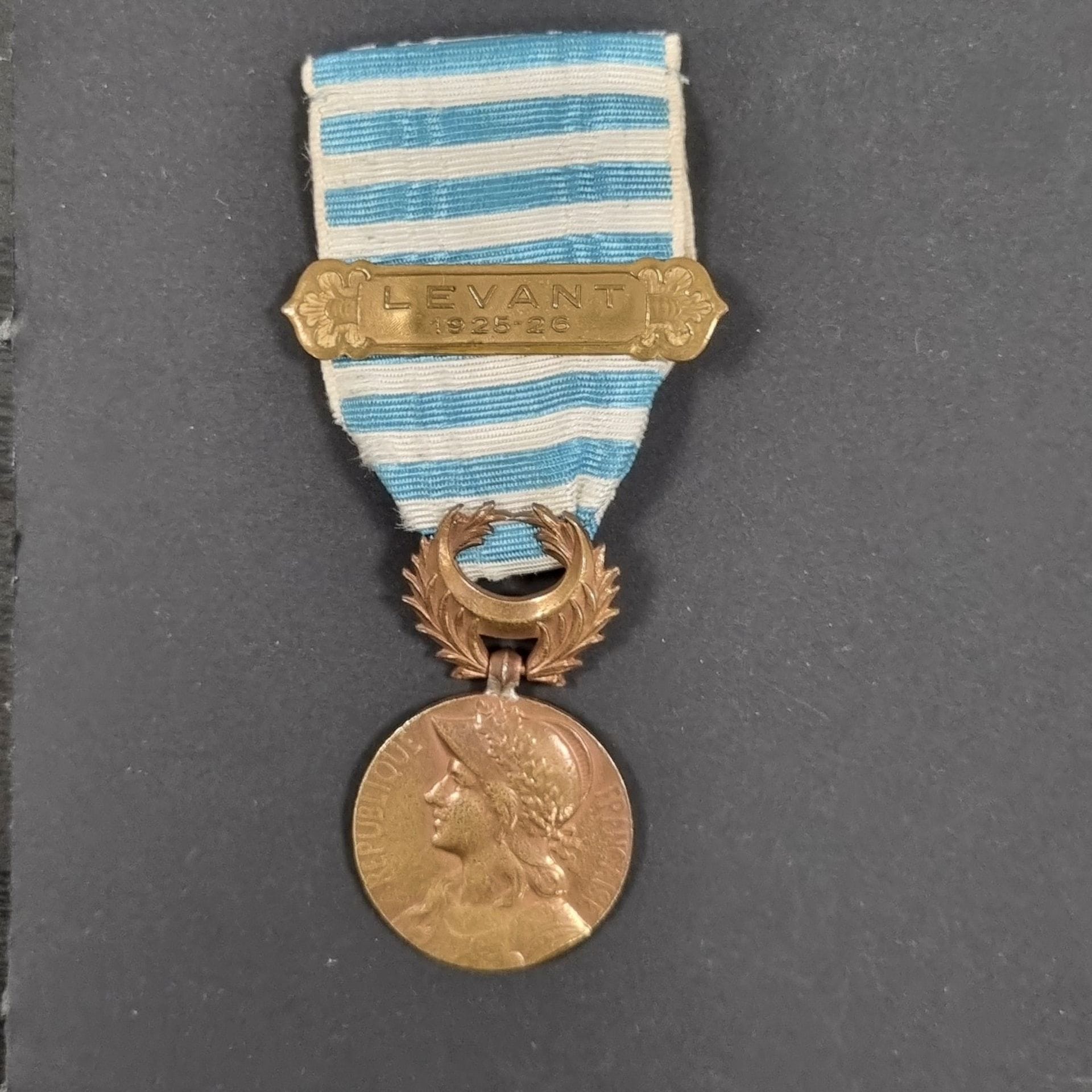 FRANCE 
MÉDAILLE DU LEVANT (1922)
Médaille en bronze (bulles), réparation entre la bélière et le jeton. 
Ruban à agrafe d’un modèle oriental « LEVANT 1925-26 ».
49 x 28 mm
T.B.