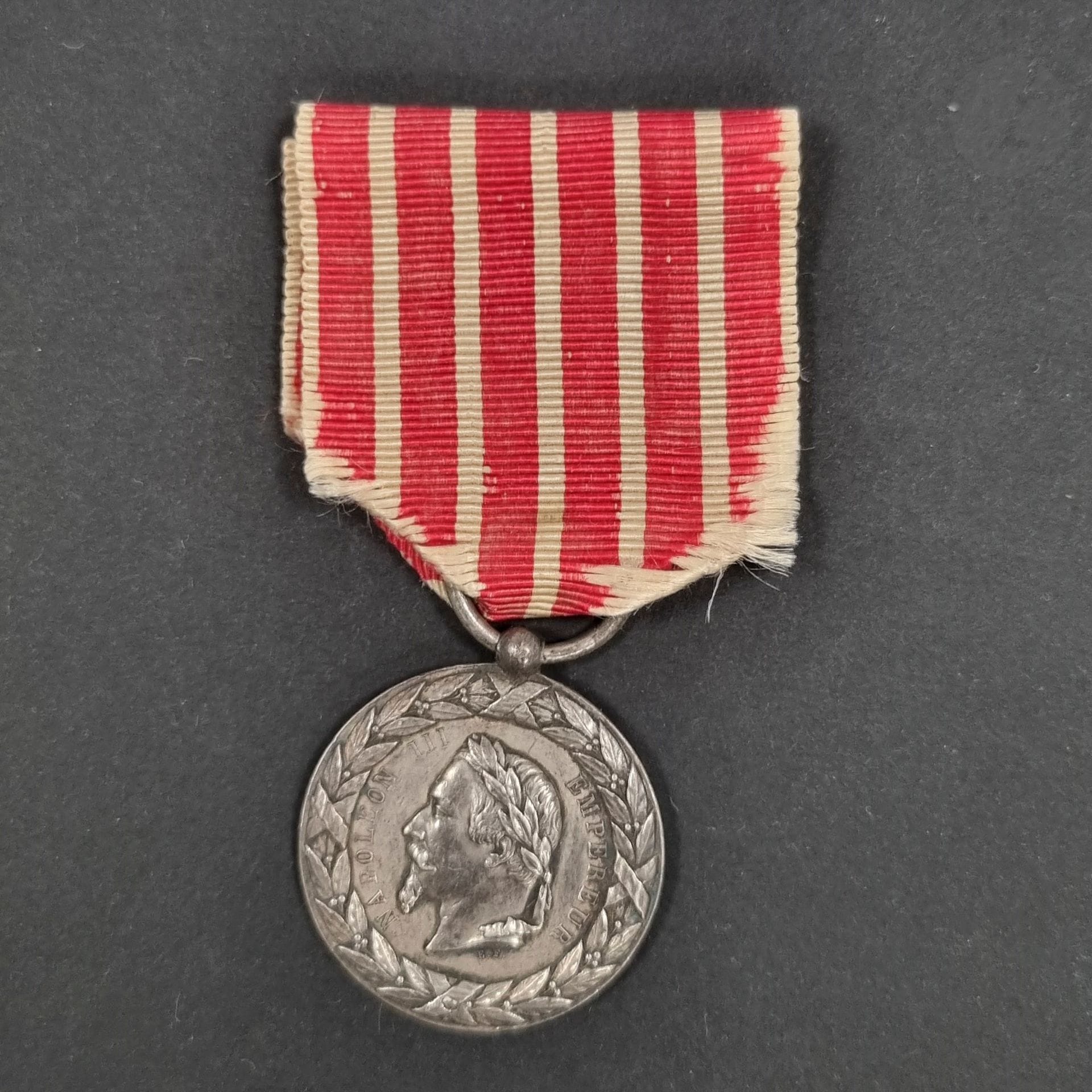 FRANCE 
Médaille de la Campagne d’Italie du 2e type signée E.F. (attribuée à Eugène Farochon). 
En argent. Ruban (usures). Poinçon tête de sanglier.
29 mm - Poids net : 12 g 
T.T.B.
