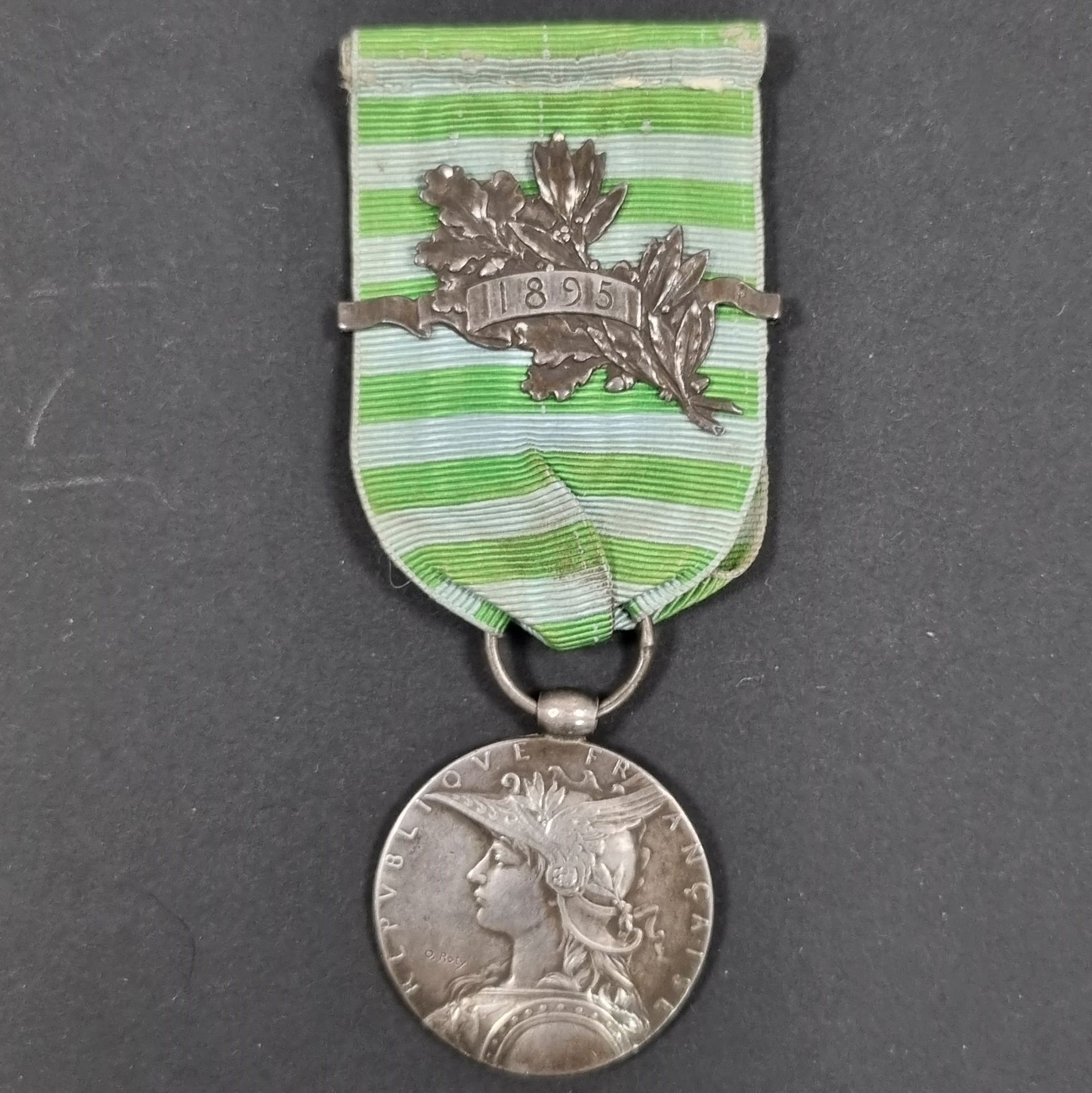 FRANCE 
MÉDAILLE DE MADAGASCAR (1895) 
Médaille par Roty.
En argent. Bélière olive. Poinçon de la Monnaie sur la tranche. Ruban avec une agrafe « 1895 ». 
28 mm - Poids brut : 18 g 
T.T.B.
