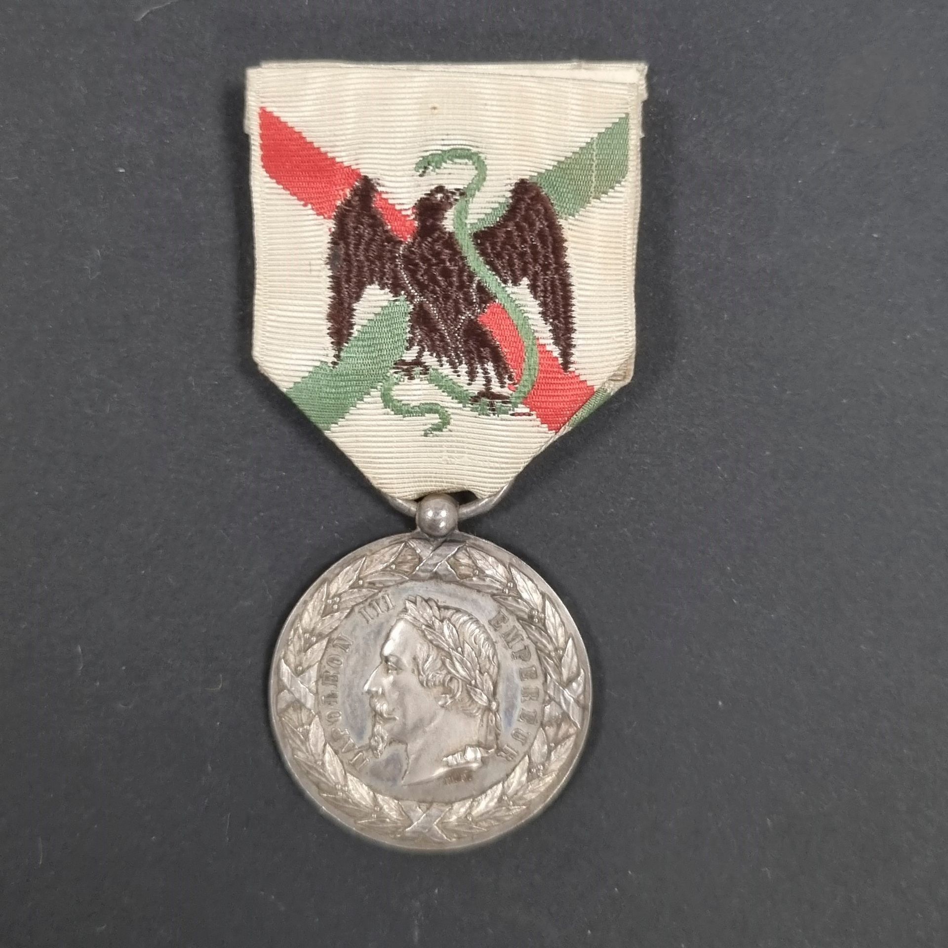 FRANCE 
Médaille de la Campagne du Mexique, signée 
« E.F. ». (attribuée à Eugène Farochon).
En argent. Ruban. 
Bélière boule. 
30 mm - Poids net : 14,4 g 
T.T.B.