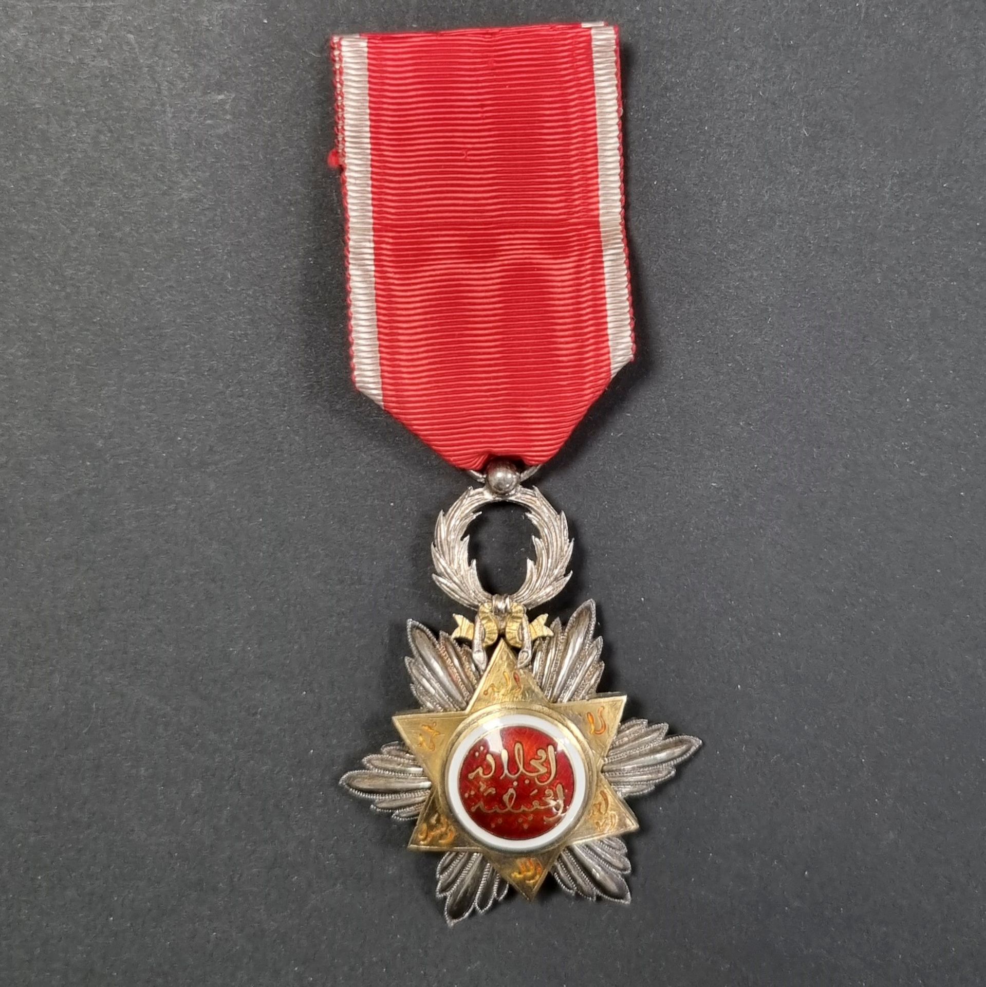 MAROC 
ORDRE DU OUISSAM HAFIDIEN (1910). 
Étoile de chevalier.
En argent, vermeil et émail (infimes éclats). Poinçon tête de sanglier et d’orfèvre (probablement Arthus Bertrand). Ruban. 
67 x 49 mm - Poids brut : 19,6 g
T.T.B.