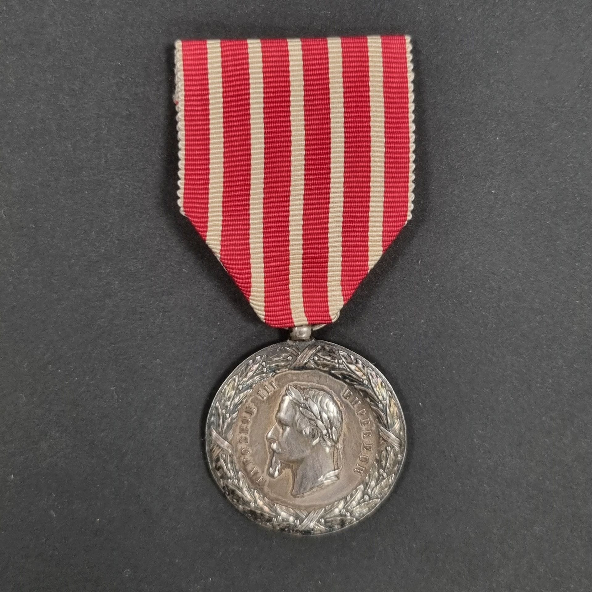 FRANCE 
Médaille de la Campagne d’Italie du 2e type, modèle non signé. 
En argent, à bélière boule. Ruban postérieur. 
Poinçon tête de sanglier sur la bélière. 
30 mm - Poids net : 12,7 g 
T.T.B.