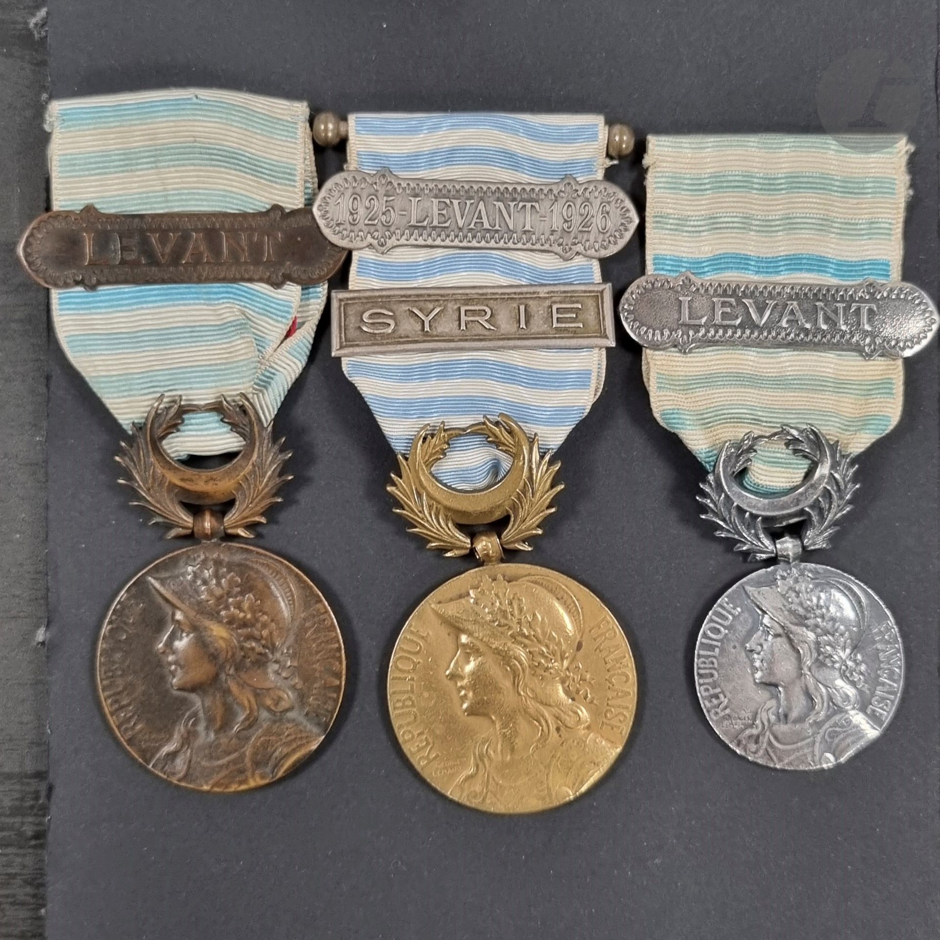 FRANCE 
MÉDAILLE DE SYRIE-CILICIE
Trois médailles : 
- une de gros module, en bronze patinée noire, poinçonnée d’Arthus Bertrand. Ruban à agrafe de style oriental en bronze patiné noir « LEVANT ». Diamètre : 35 mm
- une de gros module, en bronze, poinçonnée d’Arthus Bertrand. Ruban à deux agrafes, une de style oriental en bronze argenté 
« 1925-LEVANT-1926 », une de médaille coloniale « SYRIE ». Diamètre : 35 mm
- une de petit module, en bronze argenté, poinçonnée sur la tranche. Ruban à agrafe de style oriental en bronze argenté « LEVANT ». Diamètre : 29 mm
T.T.B.