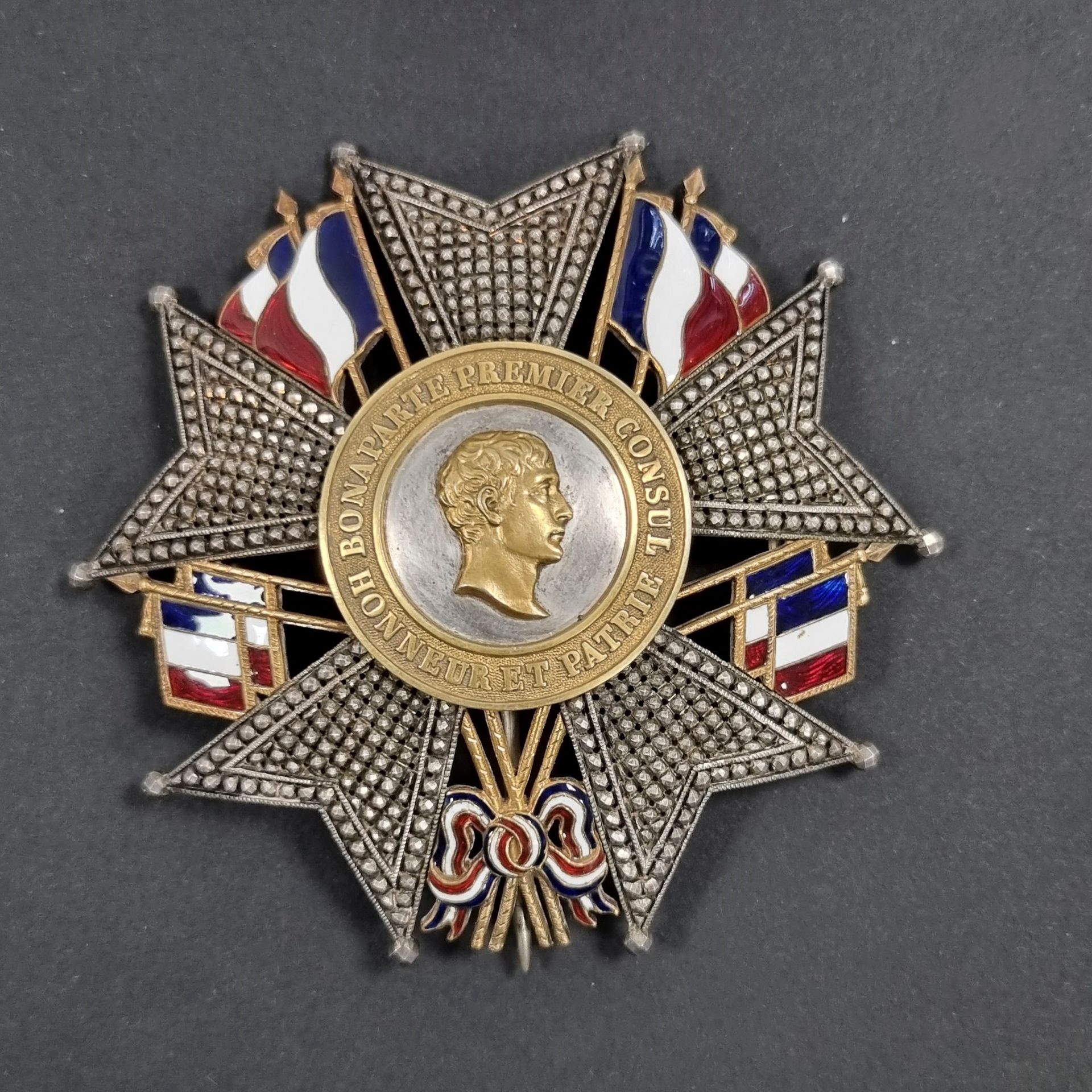 FRANCE 
ORDRE DE LA LÉGION D’HONNEUR (1802) 
Plaque métallique de grand officier ou de grand-croix, d’époque IIe République. 
En argent entièrement travaillé à pointes de diamant repercé. Entre chaque branche des drapeaux français doublés d’or émaillé tricolore. 
Centre en argent, à profil à droite de BONAPARTE et légende « BONAPARTE PREMIER CONSUL HONNEUR ET PATRIE » sur fond grenu, en or. 
Revers à deux crochets et épingle basculante. Crochet poinçonné.
82 mm - Poids brut : 56 g
T.T.B.