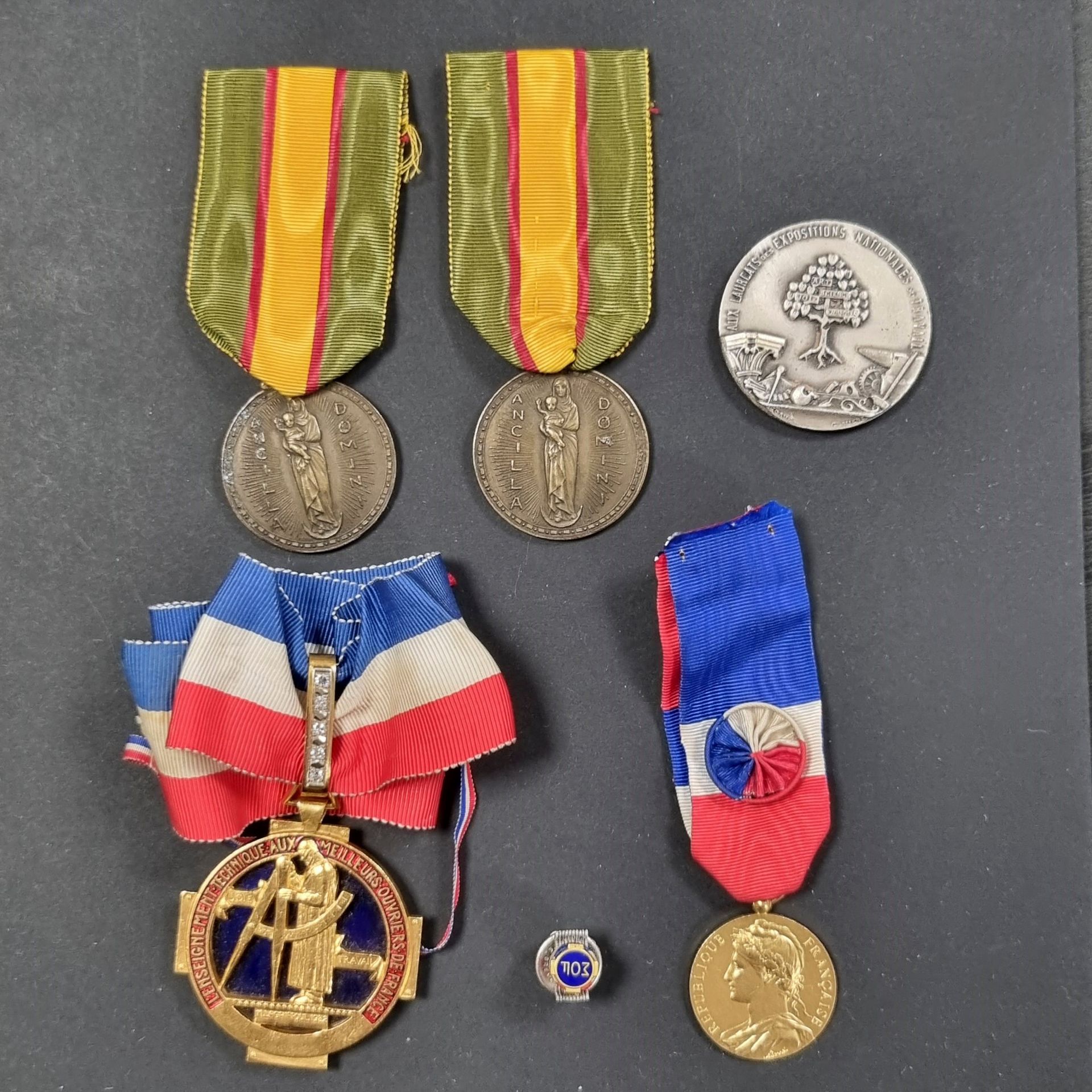 MEILLEUR OUVRIER DE FRANCE 
Insigne de sautoir de meilleur ouvrier de France. 
En bronze doré et émaillé. Attribué et daté au dos. 
Bélière en or poinçonné tête d’aigle et d’orfèvre, orné de cinq diamants taillés en rose. 
Cravate tricolore avec attache. 
Diamètre : 45 mm 
Poids net de la bélière : 3,5 g
Vers 1960.
Avec son insigne de boutonnière émaillé sur fond bleu « MOF ». 
On y joint une médaille en bronze argenté du 40e anniversaire de la fondation de la société des MOF (39 mm), deux médailles de reconnaissance du diocèse de Lyon et une médaille de travail attribué au même et à sa femme. 
T.T.B.