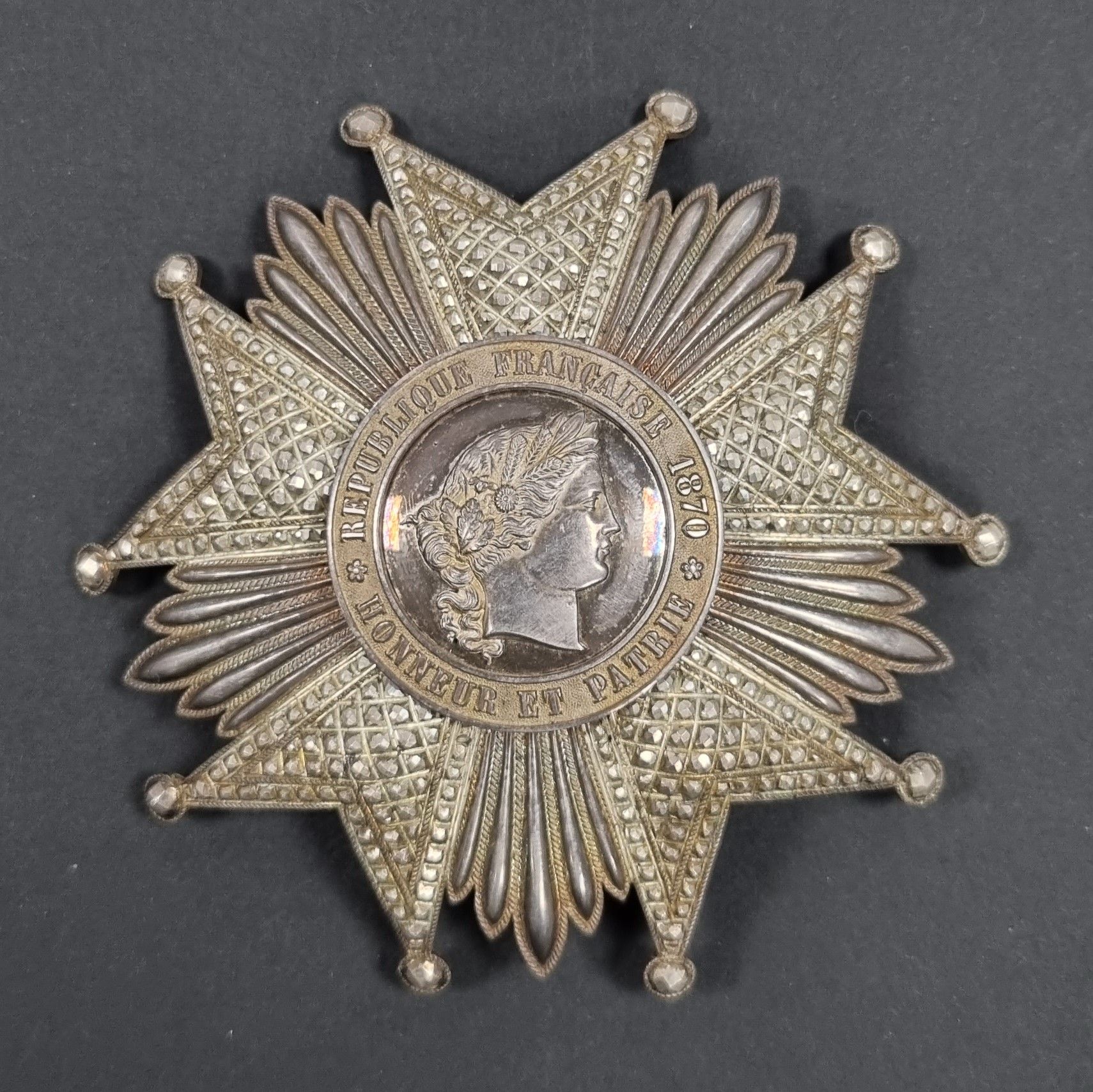 FRANCE 
ORDRE DE LA LÉGION D’HONNEUR (1802)
Plaque de grand-croix d’époque IIIe République. 
En argent, à branches travaillées à pointes de diamant, repercé. 
Le centre en plusieurs parties, au profil de Cérès. Légende « REPUBLIQUE FRANCAISE 1870 - HONNEUR ET PATRIE » sur fond grenu. 
Revers à deux crochets et épingle basculante avec pastille du fabricant « OUIZILLE LEMOINE LEMOINE FILS SUCeur JOAILLIER DE LA LÉGION D’HONNEUR RUE St HONORE 556 PARIS ». Crochet poinçonné à la tête de sanglier et d’orfèvre Ouizille Lemoine.
91 mm - Poids brut : 81 g 
T.T.B. à SUP.