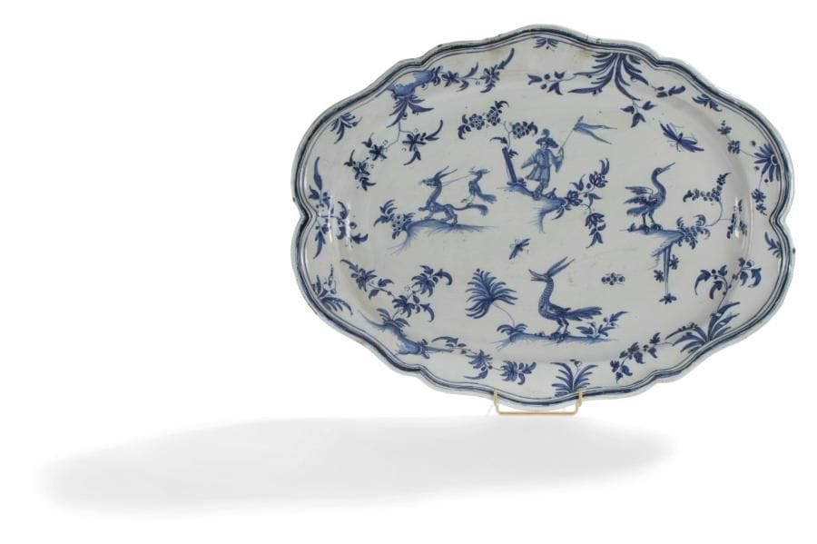 Moustiers Grand plat ovale à bord contourné à décor en camaïeu bleu d'une figure et animaux fantastiques sur quatre terrasses fleuries. Marqué au revers OLSC, atelier d'Olérys. XVIIIe siècle. Long. : 55 cm. Petites égrenures.