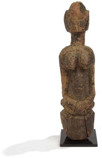 Dogon (Mali)
Statuette de personnage féminin agenouillé sur un piédestal, les bras ramenés sur le bas-ventre. Patine crouteuse. Haut. : 28,5 cm.
