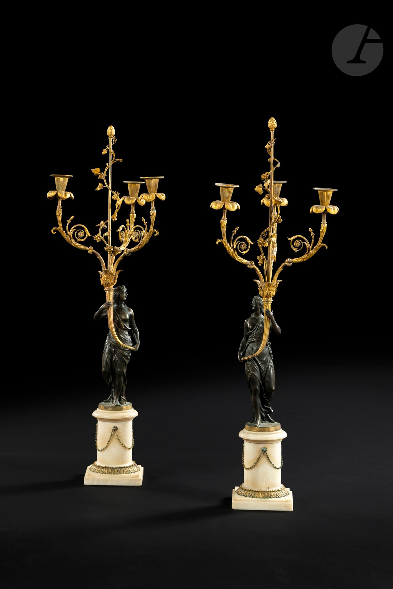 Paire de candélabres aux vestales en bronze patiné et bronze doré, à trois bras de lumière à corne d’abondance et thyrses, reposant sur une vase en marbre blanc et chainettes.

Époque Louis XVI.

Un bras cassé.

H. 86 cm