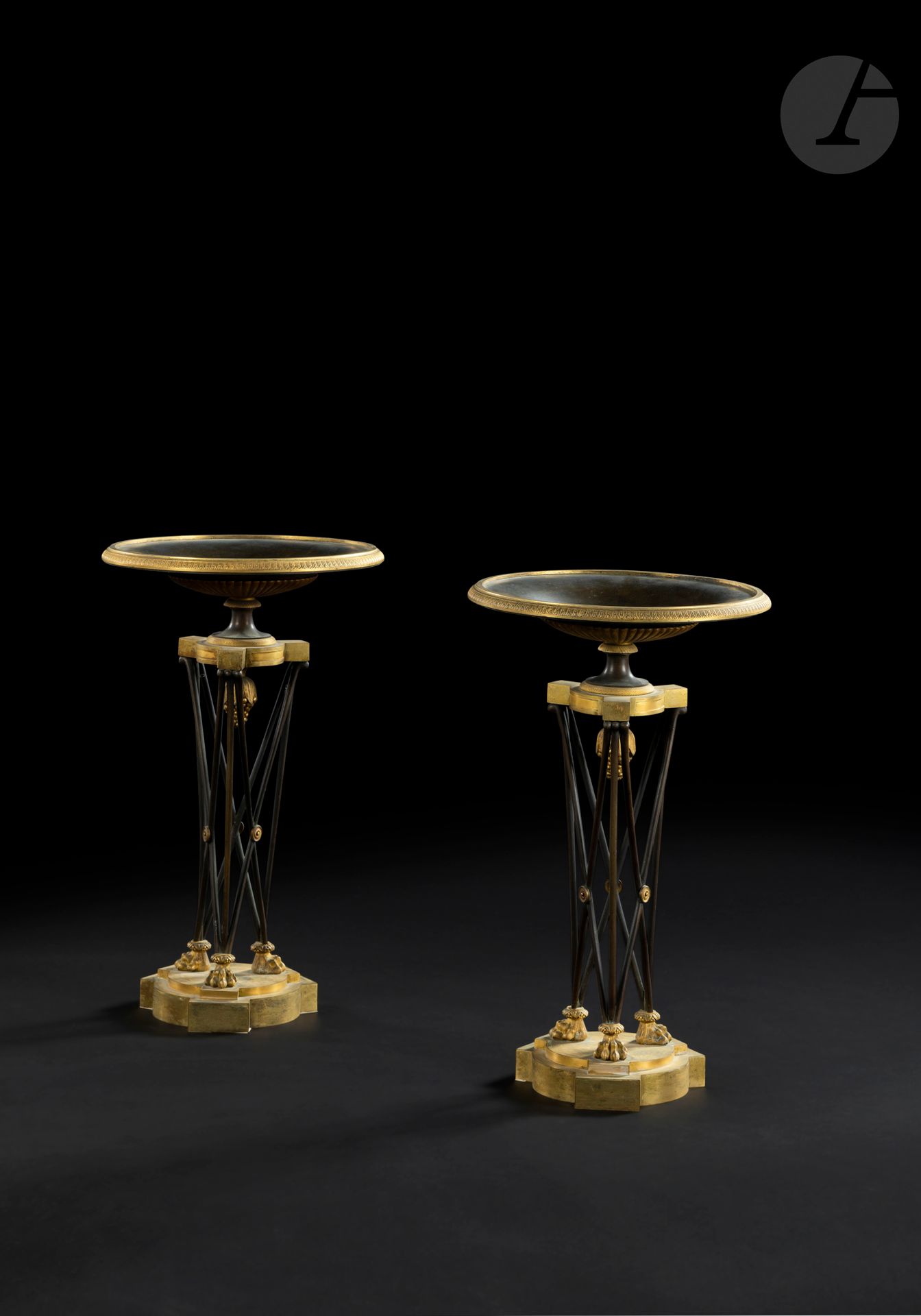 Pair of large Athenian-style bowls, in patinated bronze and gilt bronze, the tripod uprights with crosspieces and discs ending in claw feet.

Consulate period.

H. 52 cm, D. 30 cm