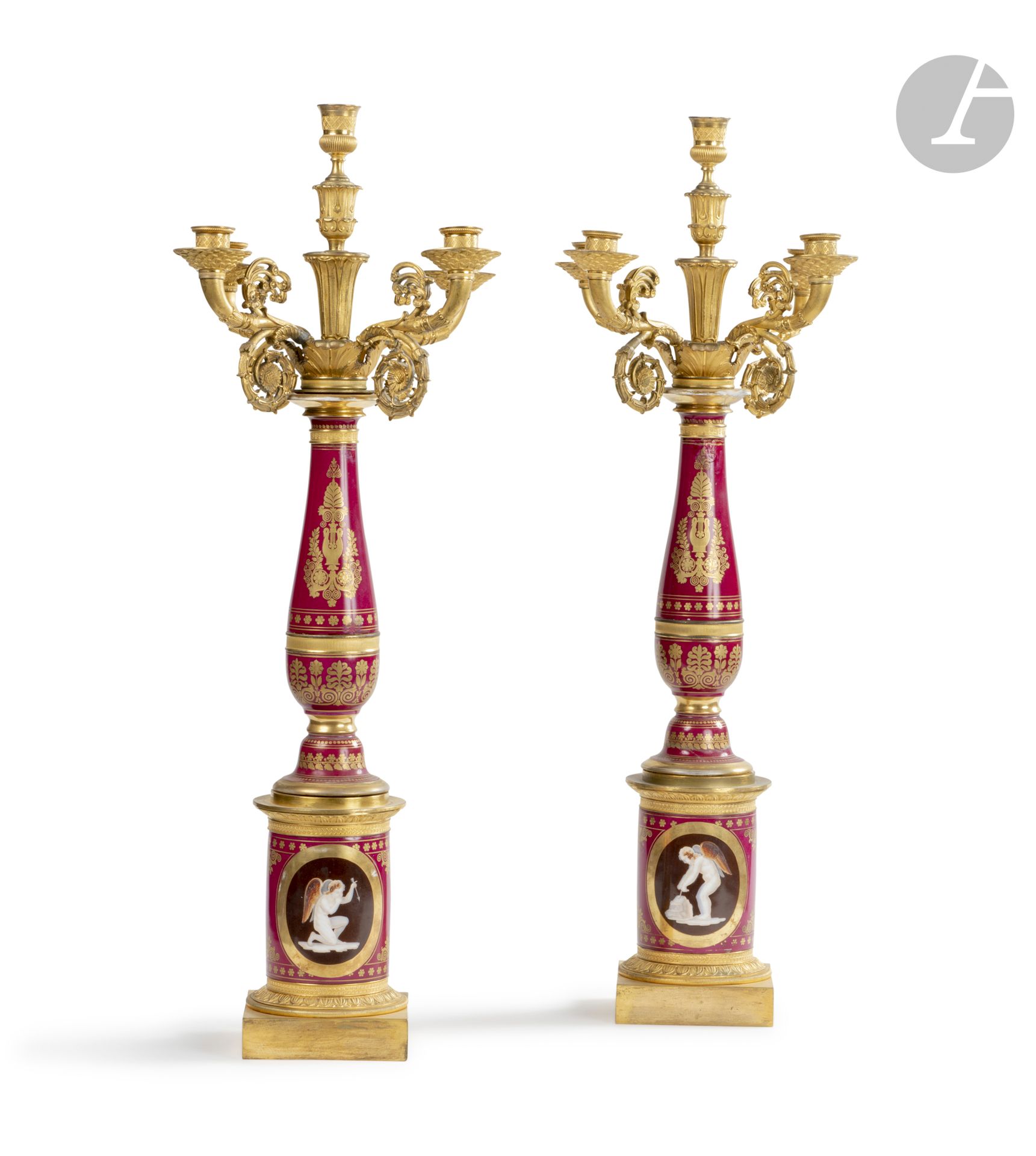 Paire de candélabres en porcelaine et bronze doré, le fût à décor rouge et or de palmettes et lyre stylisée, à cinq lumières en enroulement à rosaces, reposant sur une base à rais-de-cœur surmonté d’un fût de colonne à camées ; (restaurations).

Époque Restauration.

H. 75 cm