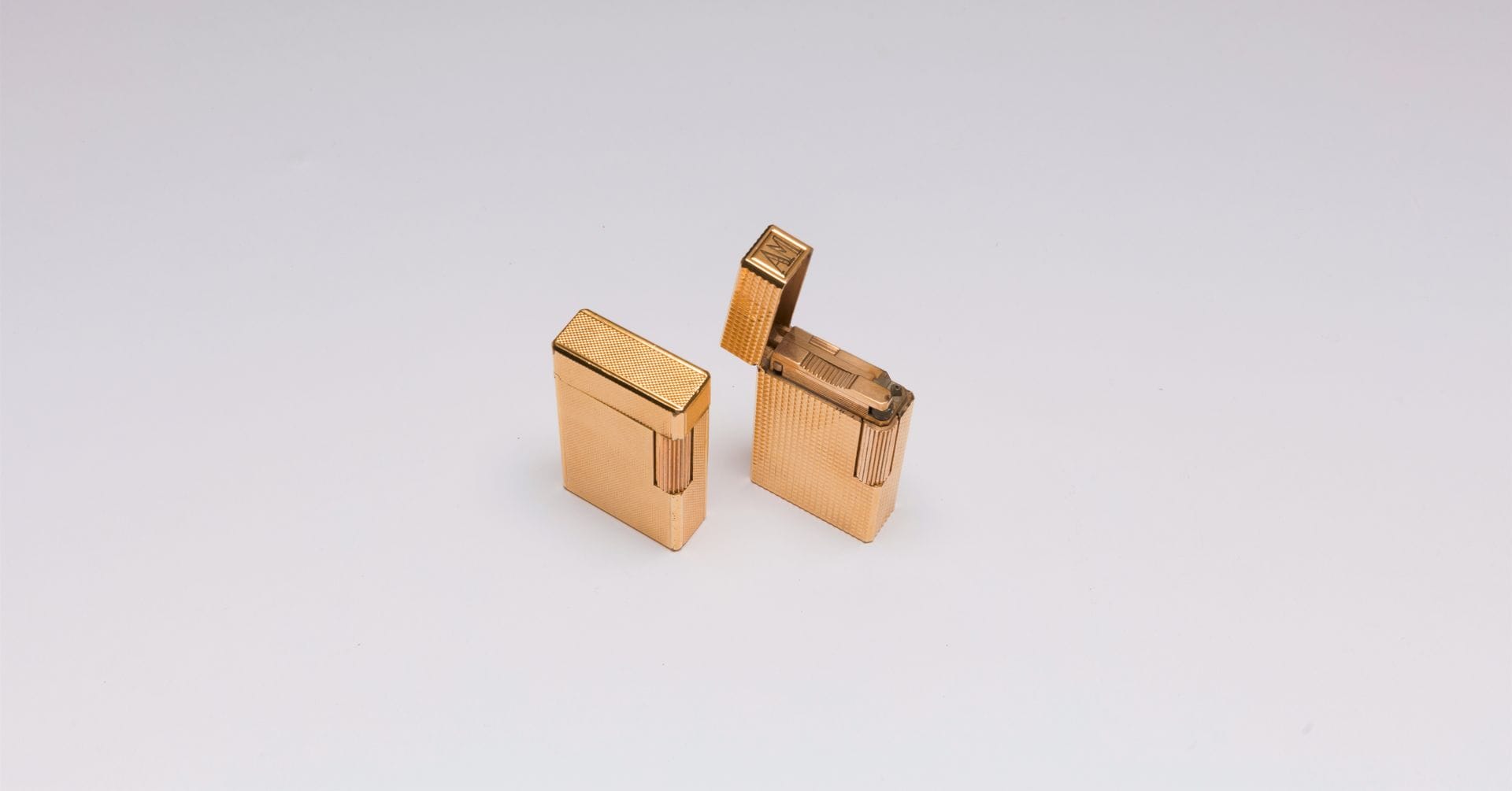 DUPONT
Suite de deux briquets en métal doré guilloché. Signés et numérotés. Hauteur : 5,8 cm environ (fonctionnement non garanti)