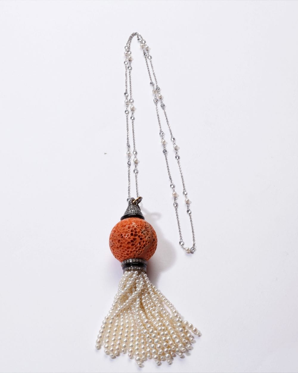 18K (750) gold and onyx pendant adorned with round old-cut and brilliant-cut diamonds, encircling a ball of raw coral holding a tassel of baroque cultured pearls, sliding on an 18K (750) white gold chain punctuated with cultured pearls and imitation diamonds. Pendant height: approx. 12.5 cm. Gross weight: 42.8 g (chips)
