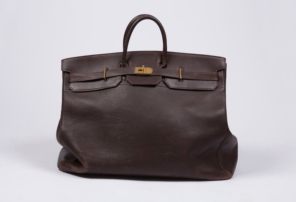 HERMÈS Paris Made in France
Sac Haut à courroies en cuir grainé marron, chiffré PET, garniture en métal doré, cadenas 55 x 44 x 27 cm (accidents dont une importante déchirure, bases des anses sectionnées, importantes usures, manque la clochette et les clés du cadenas, en l'état)