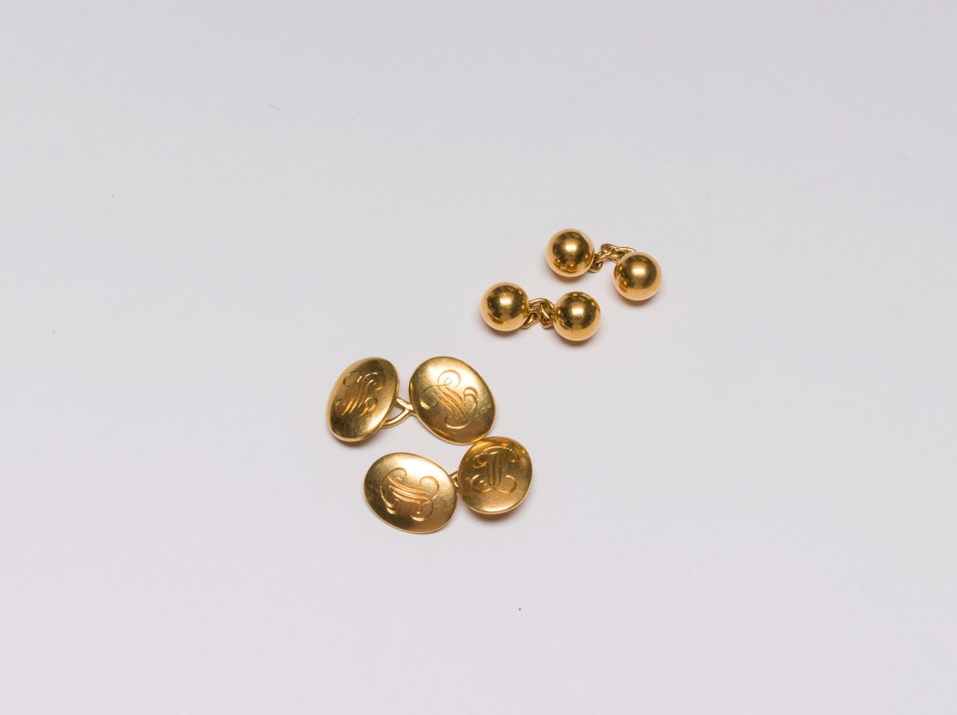 Lot de deux paires de boutons de manchettes en or 18K (750), une paire de forme ovale bombé et ornée d'un chiffre, l'autre agrémentée de boules d'or. 
Poids : 25,3 g (les boules en or creux, enfoncements)