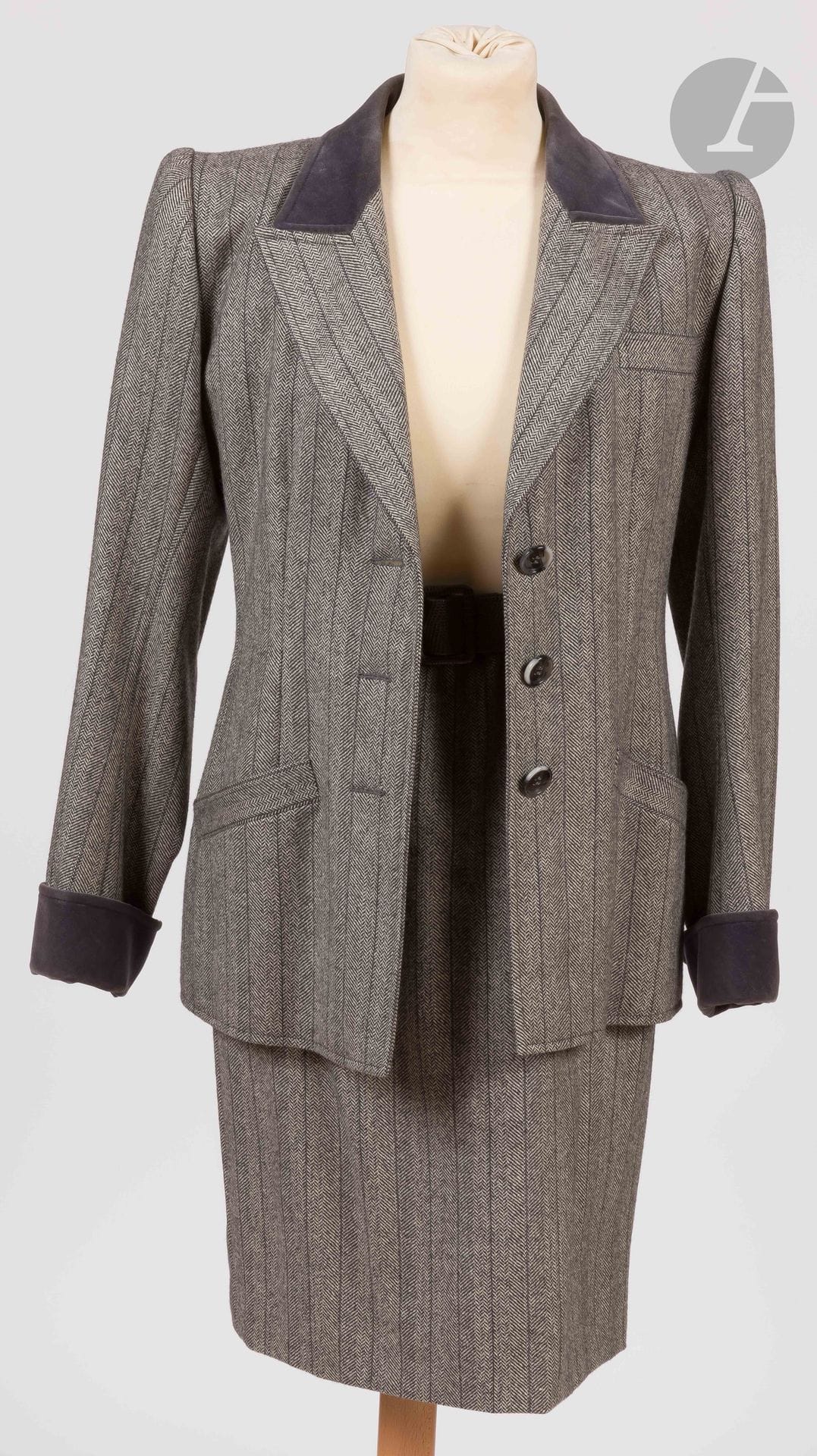 Yves SAINT LAURENT Haute Couture, années 1980
Tailleur jupe en lainage à chevrons gris et rayures noires, ceinture en cuir gris, col et revers des manches en velours gri
Taille pouvant correspondre à un 34-36 environ
