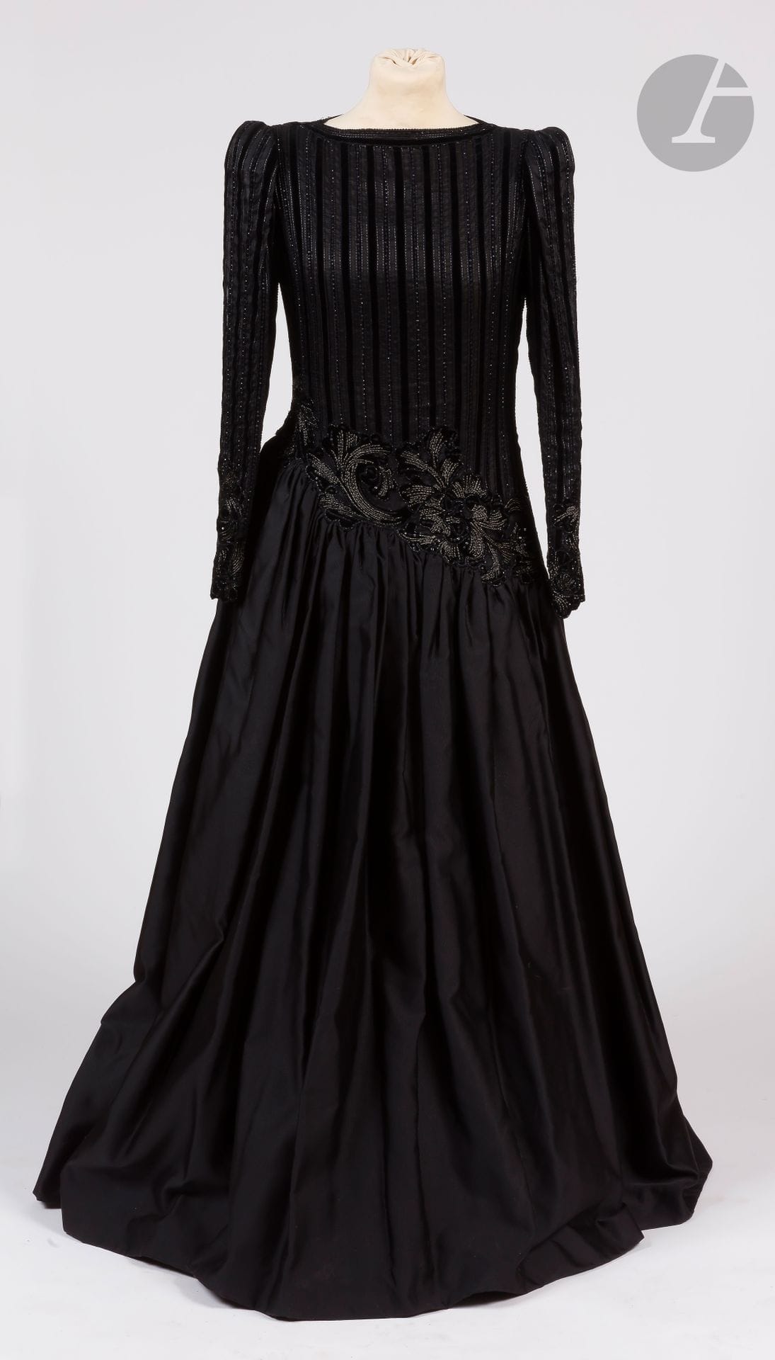 Jean-Louis SCHERRER Haute Couture, années 1980
Robe longue en soie noire, corsage entièrement brodé de bandes de velours, de perles et broderies argent, tour de taille et manches à décor de fleurs perlées (zip à revoir, rares manques de perles)
Taille pouvant correspondre à un 34-36 environ