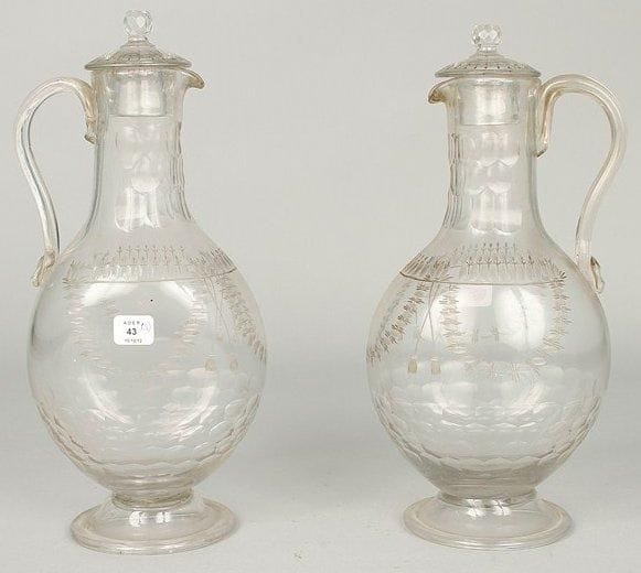 FRANCE
Deux carafes à panse aplatie, reposant sur un piédouche rond, en verre à facettes et deux bouchons. Décor de pastillages formant guirlandes de fleurs retenues par deux cordons. Et un gobelet de forme évasée. XVIIIe siècle. H: 27 cm.
