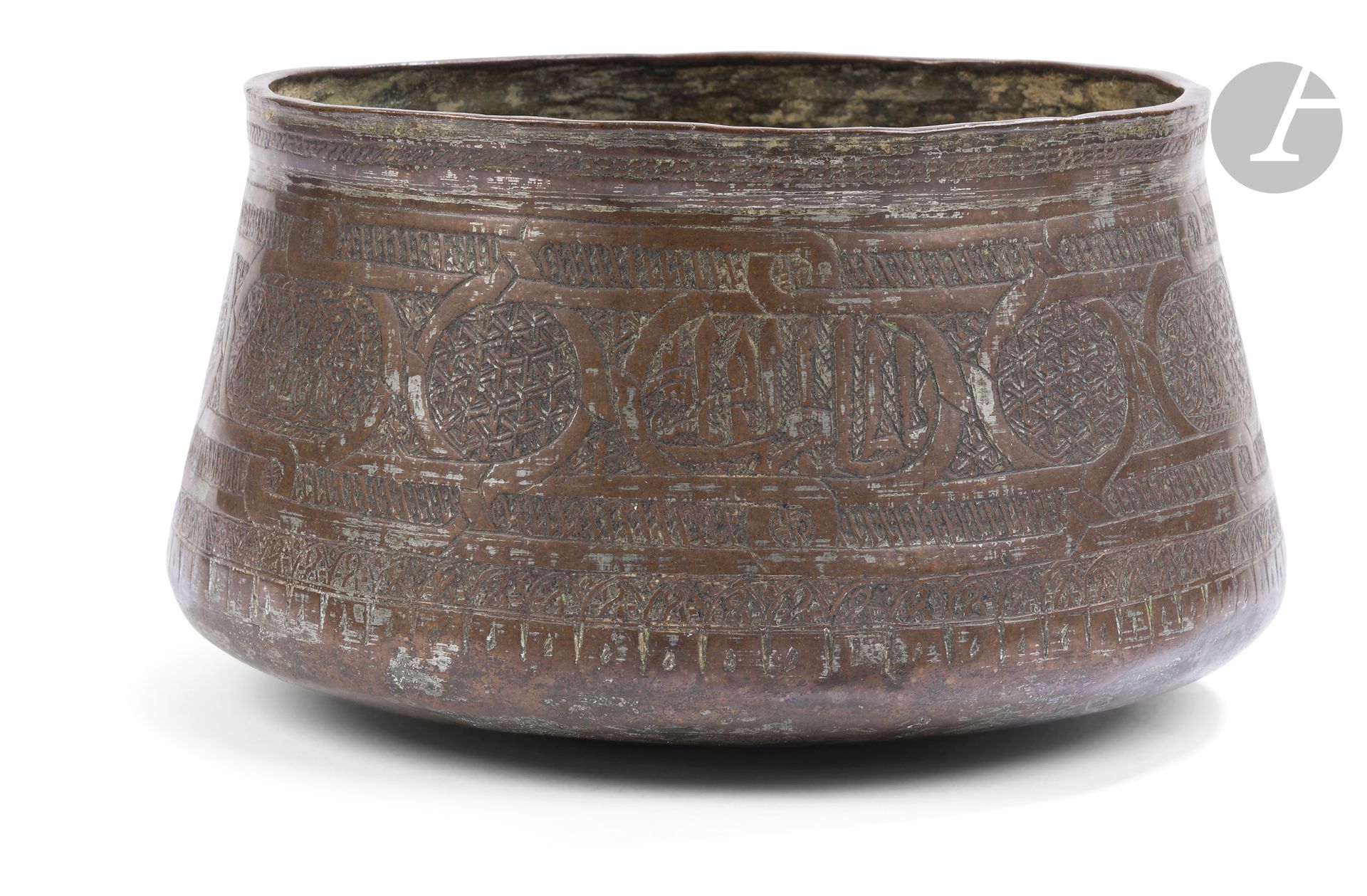 Petit bassin, Égypte mamluk, fin XVe siècle 
En bronze étamé, à panse légèrement tronconique, lèvre droite et fond bombé, décor gravé d’un bandeau de cartouches alternativement épigraphiques et à décor de palmettes, et interrompus par des médaillons circulaires garnis de Y imbriqués. Bandeau tressé de part et d’autre et frise de esses soulignant la lèvre.
Diam. ouverture : 19,5 cm
Chocs et usures.

A Small Mamluk Bronze Basin, Egypt, late 15th Century