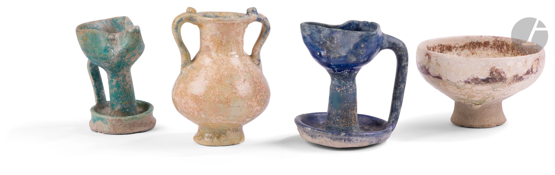 Quatre céramiques médiévales, Iran et Syrie, XIIe - XIIIe siècle
En céramique siliceuse glaçurée. - La première, pot à lait sur petit piédouche, à panse piriforme surmontée d’un col cylindrique à lèvres éversées flanqué de deux anses sinueuses agrémentées d’une petite protubérance sur le dessus. La glaçure transparente rehaussée de bleu cobalt sur les lèvres et sur les anses ; - la deuxième, petite coupe à panse carénée sur piédouche à décor de lustre métallique brun à l’intérieur et soulignant la lèvre à l’extérieur ; - les deux suivantes, petites lampes monochromes turquoise et bleu cobalt, à haut pied cylindrique posé sur un petit plateau circulaire et supportant un réceptacle à bec pincé relié au petit plateau par une anse droite.
Hauteur : 11,1 cm, 6,5 cm, 9,4 et 9,6 cm
Forte irisation et petits manques sur les deux premières pièces, légères restaurations sur le pot à lait, importantes restaurations sur les deux lampes.

Four Tiny Medieval Potteries, Iran and Syria, 12th - 13th Century