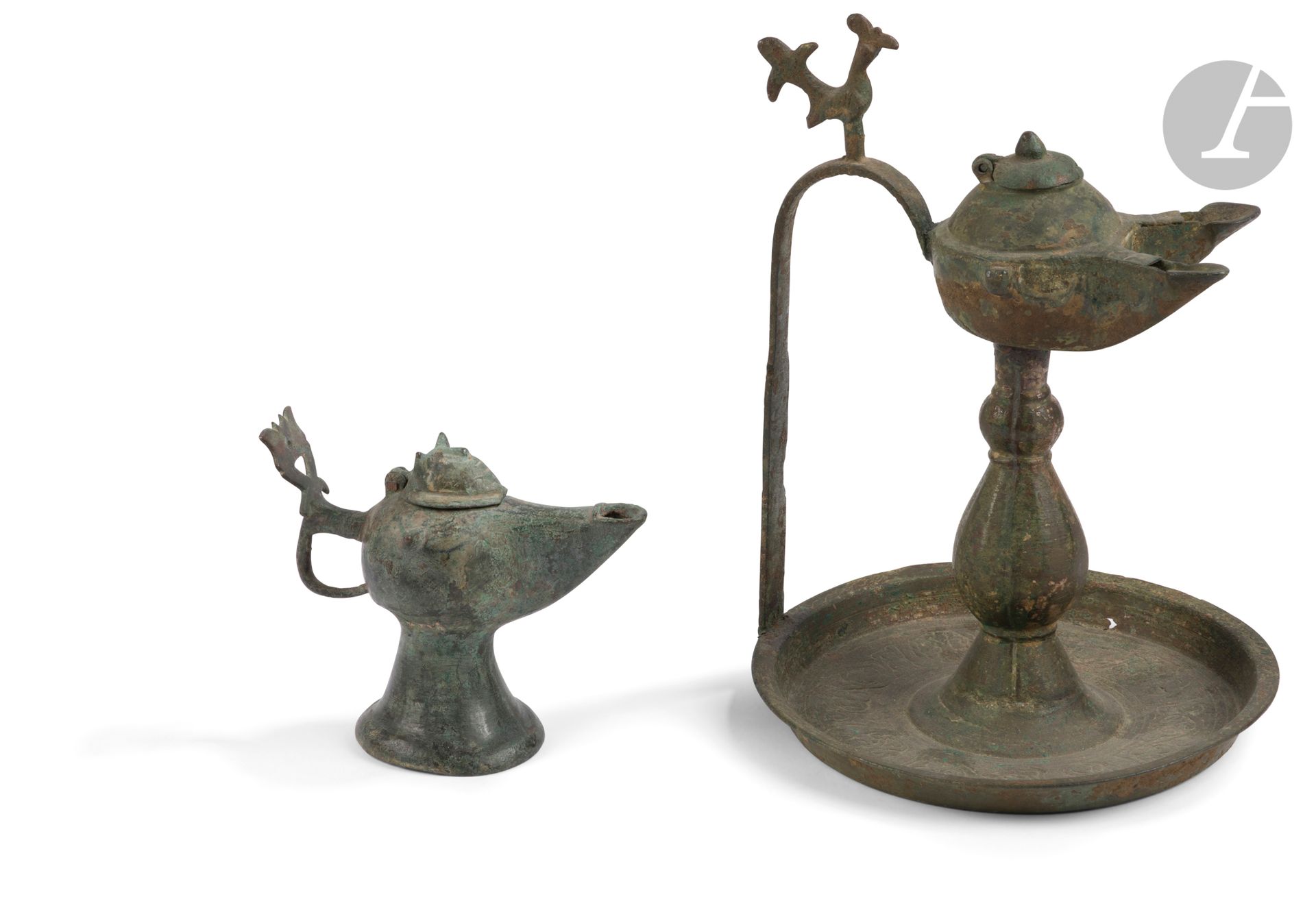 Deux lampes à huile, Iran, XIIe siècle
Lampes en bronze, la première sur haut pied balustre posé sur un plateau circulaire et supportant un réceptacle sphérique à double-bec courbe, fermé d’un couvercle en dôme et relié au plateau par une anse droite coudée surmontée d’un poucier en forme de coq. Le plateau gravé d’une frise de rinceaux interrompue par des rondeaux tréflés ; la seconde, petite lampe sur haut piédouche à long bec courbe pincé sur les flancs, présentant deux protubérances latérales, munie d’une anse annelée à poucier végétal et fermée d’un couvercle en protomé de félin.
H. max. : 23,5 cm et 10,5 cm
Concrétions, restaurations, perforation dans le plateau de la première, cassure sur le couvercle de la seconde présentant un petit manque à la base.
 
Two Bronze Oil Lamps, Iran, 12th Century