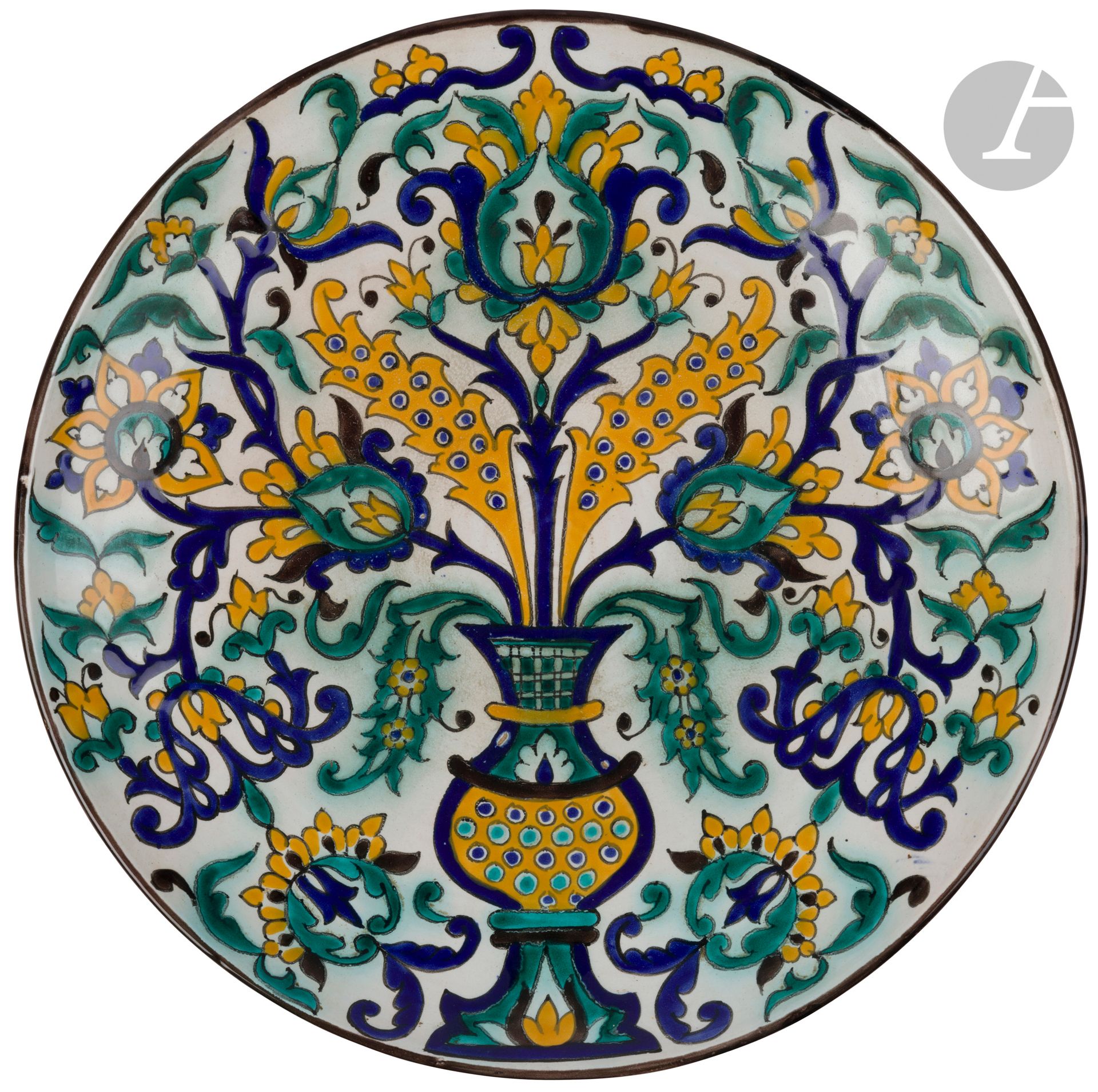 Grand plat à décor floral, Tunisie, Nabeul, atelier ‘Abderrazaq, milieu du XXe siècle
Important plat sur grand pied circulaire en faïence à décor peint dans les tons jaune, vert, bleu et brun d’un vase contenant un bouquet mêlant fleurs composites et feuilles saz dans le style de la céramique ottomane. Sous le pied, inscription en arabe : « ‘Abderrazaq Nabeul ».
Diamètre : 43 cm
Deux trous de suspension.

A Large Dish, Tunisia, Nabeul, ‘Abderrazaq factory, mid-20th Century