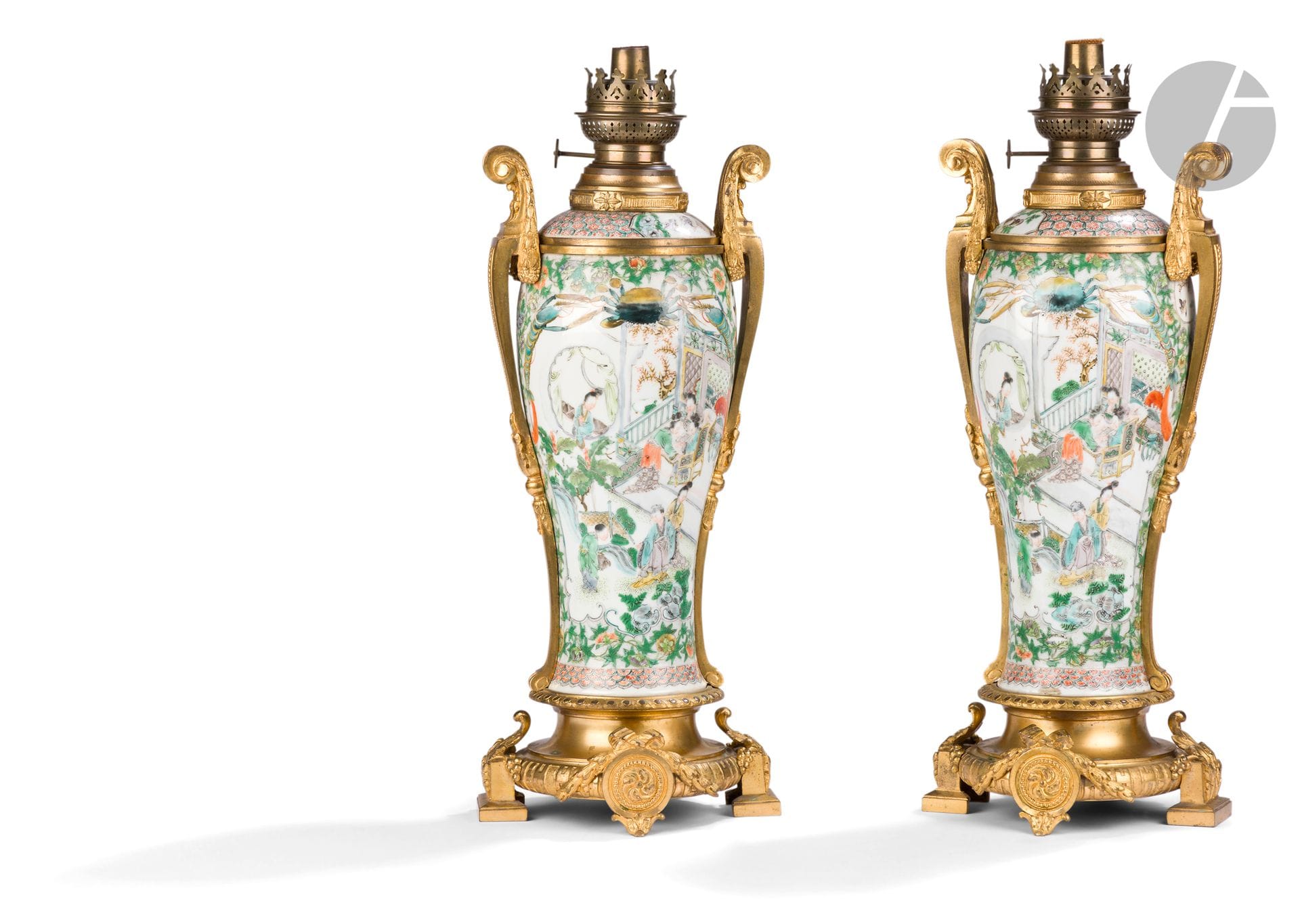 Paire de vases en porcelaine dans le style de la famille verte, montés en lampe à pétrole, Chine, Canton, XIXe siècle
De forme balustre, chaque panse est ornée de deux réserves à décor de dignitaires, cavaliers, jeunes femmes, enfants et serviteurs s’adonnant à leurs occupations dans un riche pavillon, sur une terrasse ou dans un jardin. Chaque médaillon est décoré en partie haute d’un gros crabe et deux écrevisses. Les couvercles sont à décor d’oiseaux dans des cartouches sur un fond stylisé. Les vases sont insérés dans une importante monture en bronze doré européenne du XIXe siècle pour former une paire de lampes à pétrole.
H. totale : 49 cm