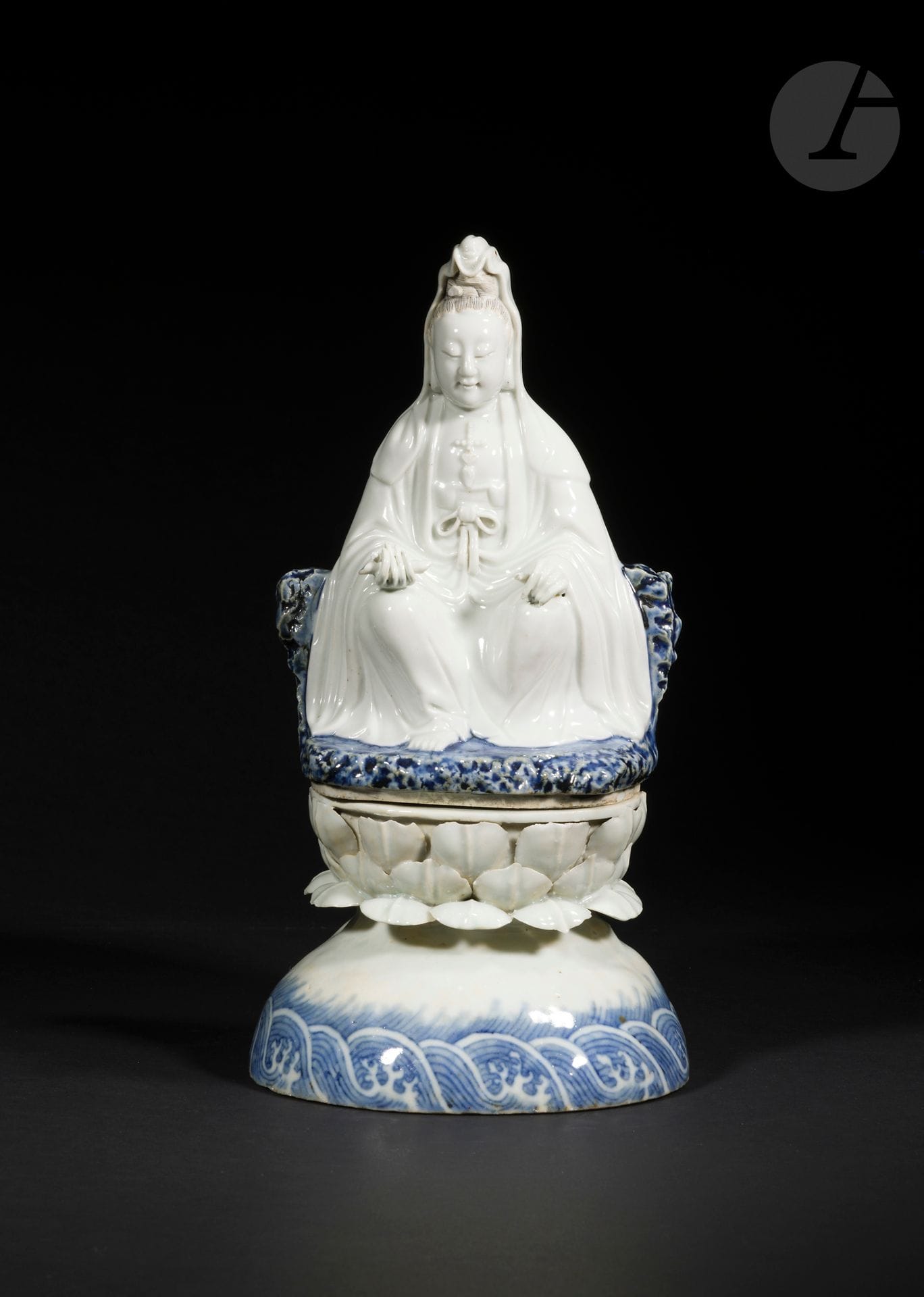 Blue and white porcelain Guanyin, China, 19th century, on a lotiform base, Japan, 19th century
In white porcelain, seated on a mound imitating a rock, glazed in blue underglaze, a scroll in her right hand, her chest adorned with pearls evoking a Christian cross. The upper part of the base is adorned with lotus petals in relief, and the base is decorated in underglaze blue with foaming waves.
Total height: 30 cm
Restoration to the hands and missing parts, and restoration to the base. Small chips.