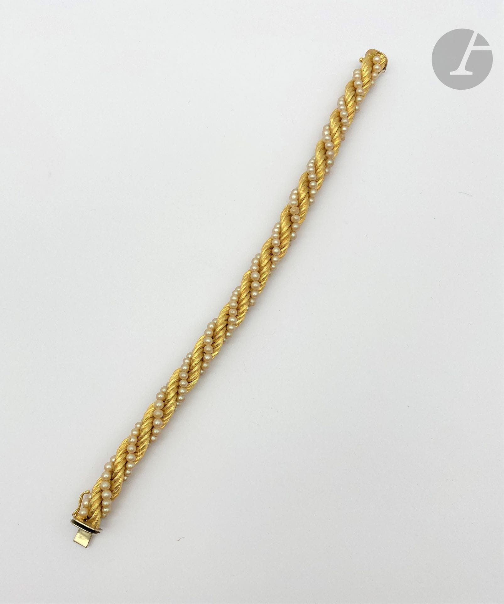 Bracelet en torsade d'or 18K (750) tressé alterné de perles fantaisie. 
Longueur : 20 cm environ. Poids brut : 25,4 g (choc, égrisures)