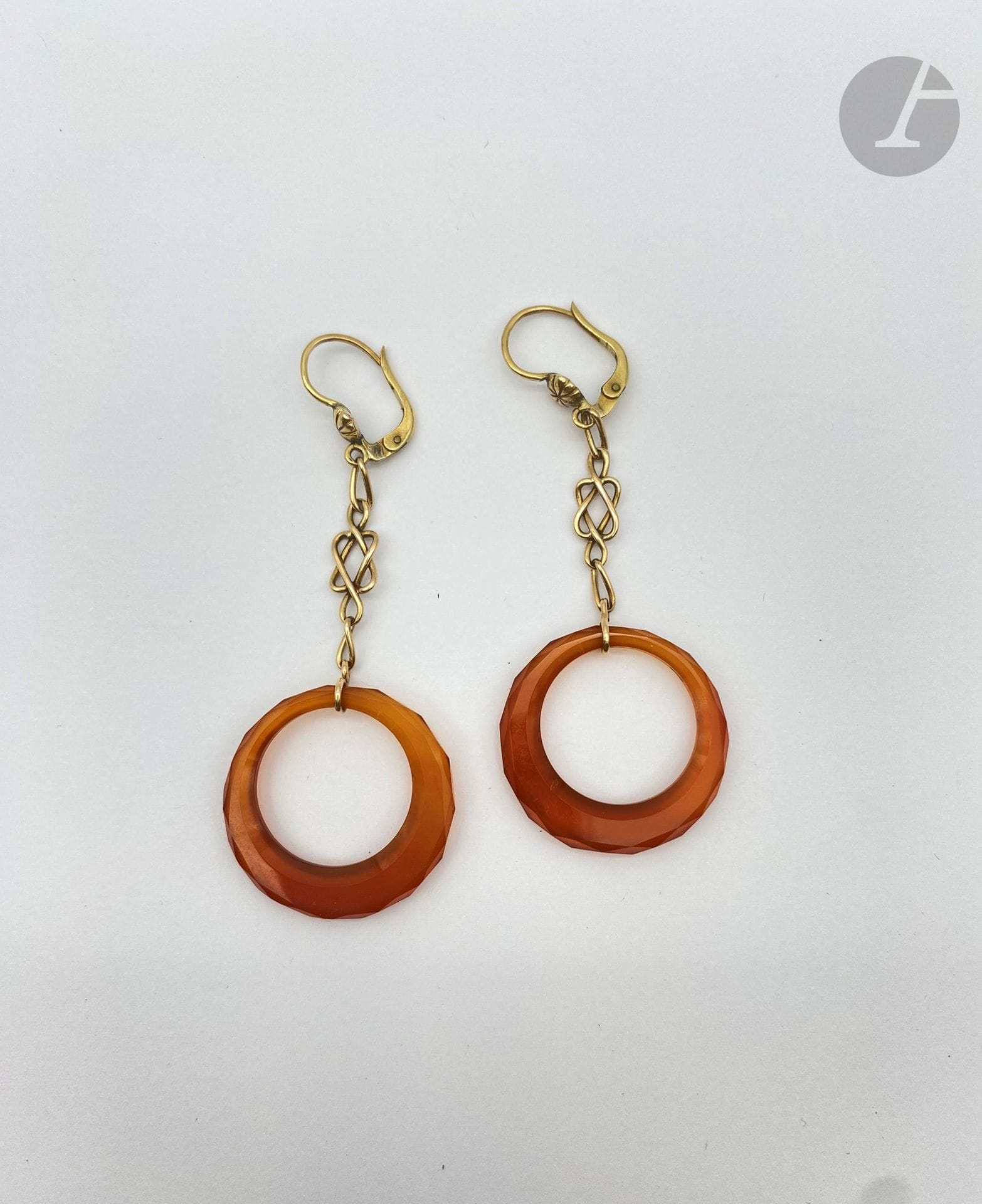 Paire de pendants d'oreilles en or 18K (750) retenant un anneau facetté de cornaline. 
Longueur : 7 cm environ. Poids brut : 7,6 g