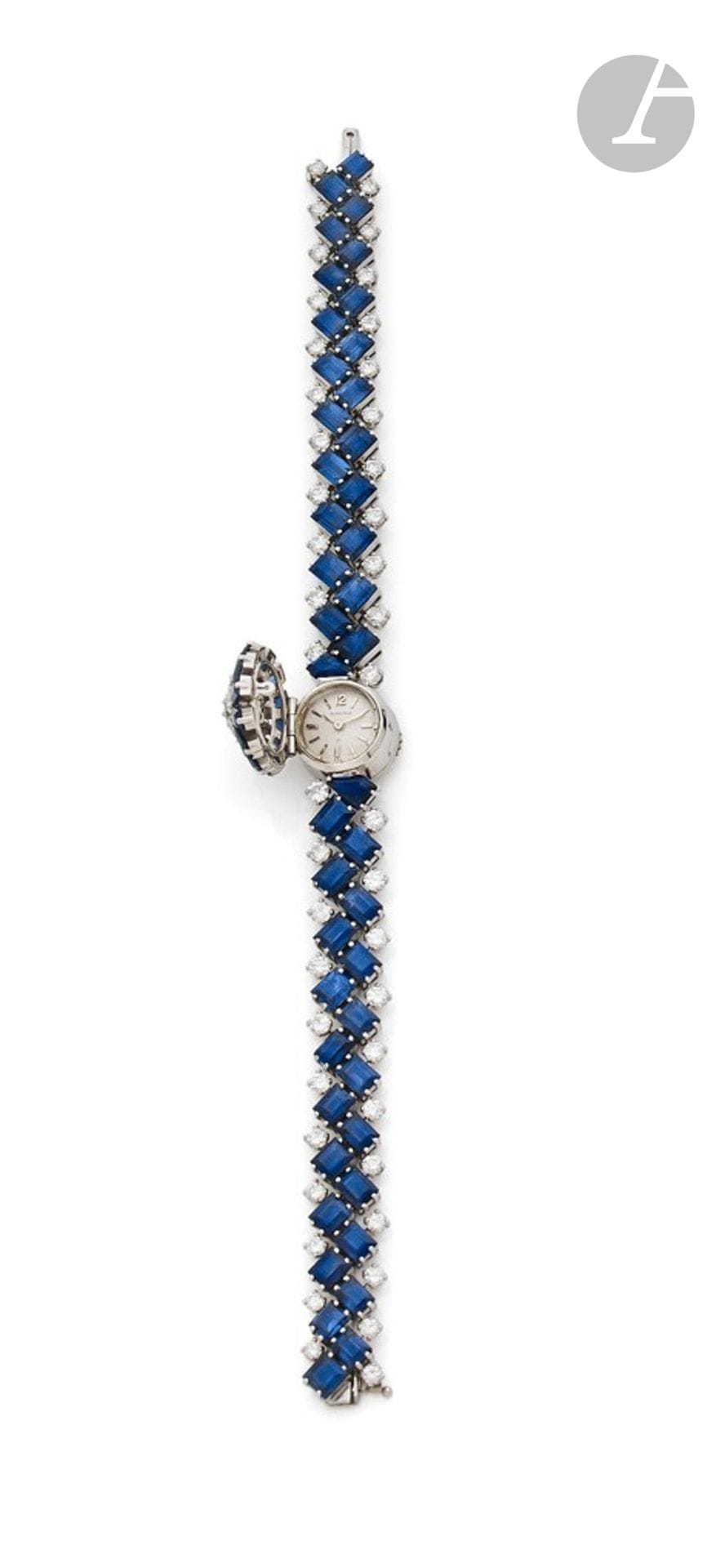 BLANCPAIN-UTI
ANNÉES 60
Montre bracelet de dame à capot en platine (950), diamants et saphirs naturels. Travail français. 
Boîtier : rond en platine, remontoir au dos, capot centré de diamants (taille brillant et un taille ancienne) dans un entourage de saphirs baguette.?Cadran : argenté, signé Blancpain-Uti.
Mouvement : mécanique, duoplan, signé Blancpain/Rayville S.A., cal. R 550, 17 rubis, swiss. ?Bracelet : articulé, saphirs rectangulaires à pans en quinconce et diamants, monture en platine, boucle simple.
Cadran et mouvement signés. ?Numérotée 75150. 
Diam. 18 mm - Long. : 17,5 cm. 
Poids brut : 50,62 g.