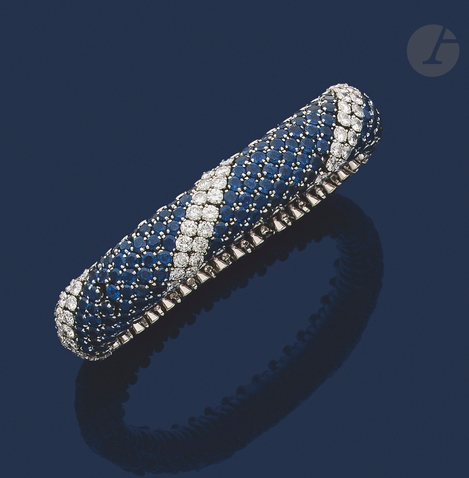 Bracelet ruban souple en fils d'or gris, bombé, entièrement pavé de lignes de saphirs ronds alternées de lignes de diamants ronds de taille brillant. Travail français des années 1970. Dimensions : 18 x 1,5 cm environ. Poids brut : 76,9 g (chocs)

A French 1970 sapphires and diamonds bracelet