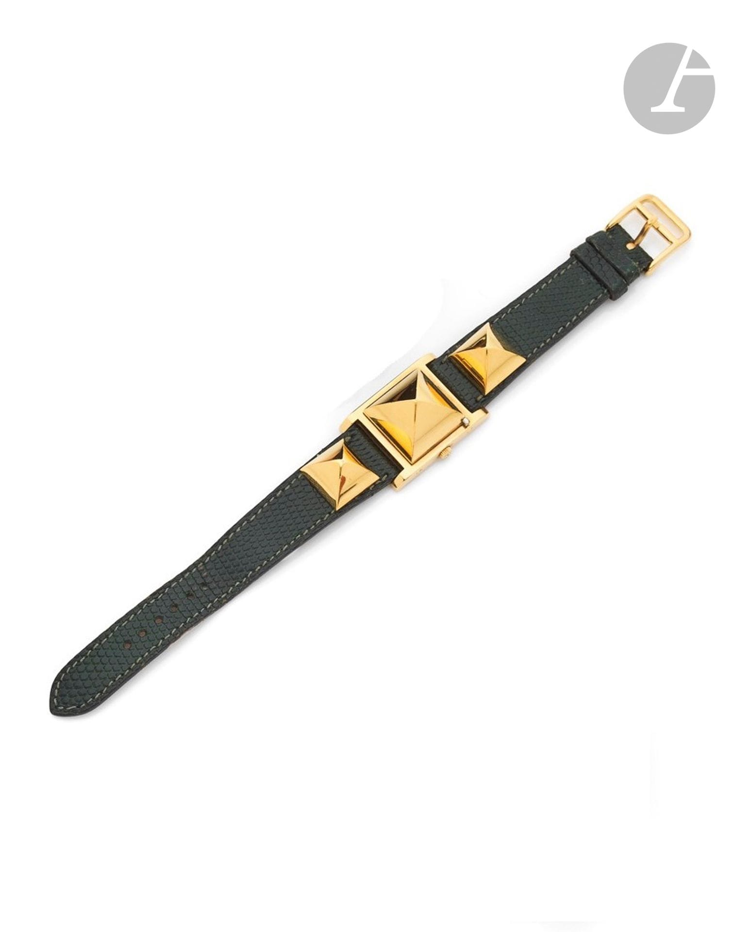 HERMÈS
MEDOR
Montre bracelet de dame en métal doré sur cuir. 
Boîtier : carré en métal doré à capot, de forme " pain de sucre ", fond en acier. 
Cadran : argenté, index appliqués aux quarts. 
Mouvement : quartz.
Bracelet : cuir,  deux " pains de sucre " en métal doré vissés sur le cuir, boucle ardillon en métal doré Hermès. 
Signée et numérotée 611727. 
Diam. 23 mm. 
Avec : pochon Hermès. 
(Pile à changer, fonctionnement non garanti)