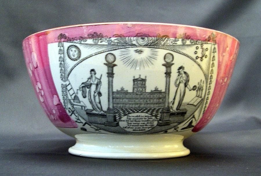 Grand bol en faïence fine à décor imprimé et peint sur fond irisé rose. L'extérieur est décoré de trois panneaux, l'un représente un tableau de loge avec au centre des deux colonnes le Temple de Salomon, sur les cotés les trois vertus et les outils, le second représente un trois mats dénommé "Northumberland 74", et le troisième une maxime sur la vie. L'intérieur est aussi orné de trois panneaux se rapportant à l'alliance franco-britannique, un panneau représente deux fantassins avec leur drapeau national qui se serrent la main, le second représente la même scène mais avec deux marins. Le troisième cartouche représente en médaillon Napoléon III et la reine Victoria, les étendards nationaux avec et la formule "May they ever be united".  Angleterre vers 1855. Rare (diam. 25 cm.  haut. 12,5 cm). Ce bol commémore l'alliance entre Napoléon III et de la reine Victoria contre la Russie qui débuta par la guerre de Crimée en 1853. 